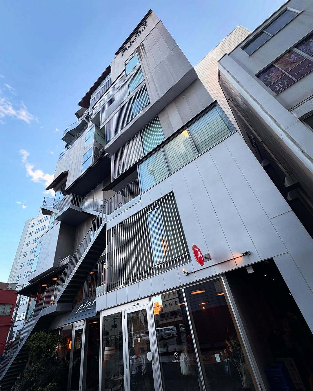 نمای ساختمان ناین آورز آساکوسا در توکیو که طی سال‌های ۲۰۱۸ تا ۲۰۲۵ از هتل کپسولی به برج سونا تغییر کاربری داده و اکنون تنها کافه نروژی FUGLEN در طبقه همکف آن فعال است؛ تصویری مرتبط با معماری و تغییرات کاربری بنا در منطقه آساکوسا.