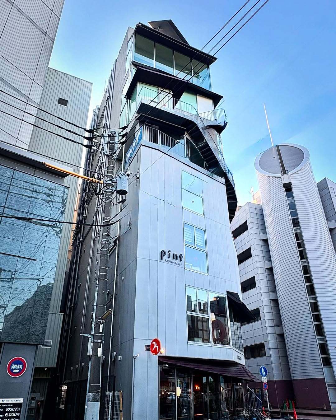 نمای ساختمان ناین آورز آساکوسا در توکیو که طی سال‌های ۲۰۱۸ تا ۲۰۲۵ از هتل کپسولی به برج سونا تغییر کاربری داده و اکنون تنها کافه نروژی FUGLEN در طبقه همکف آن فعال است؛ تصویری مرتبط با معماری و تغییرات کاربری بنا در منطقه آساکوسا.