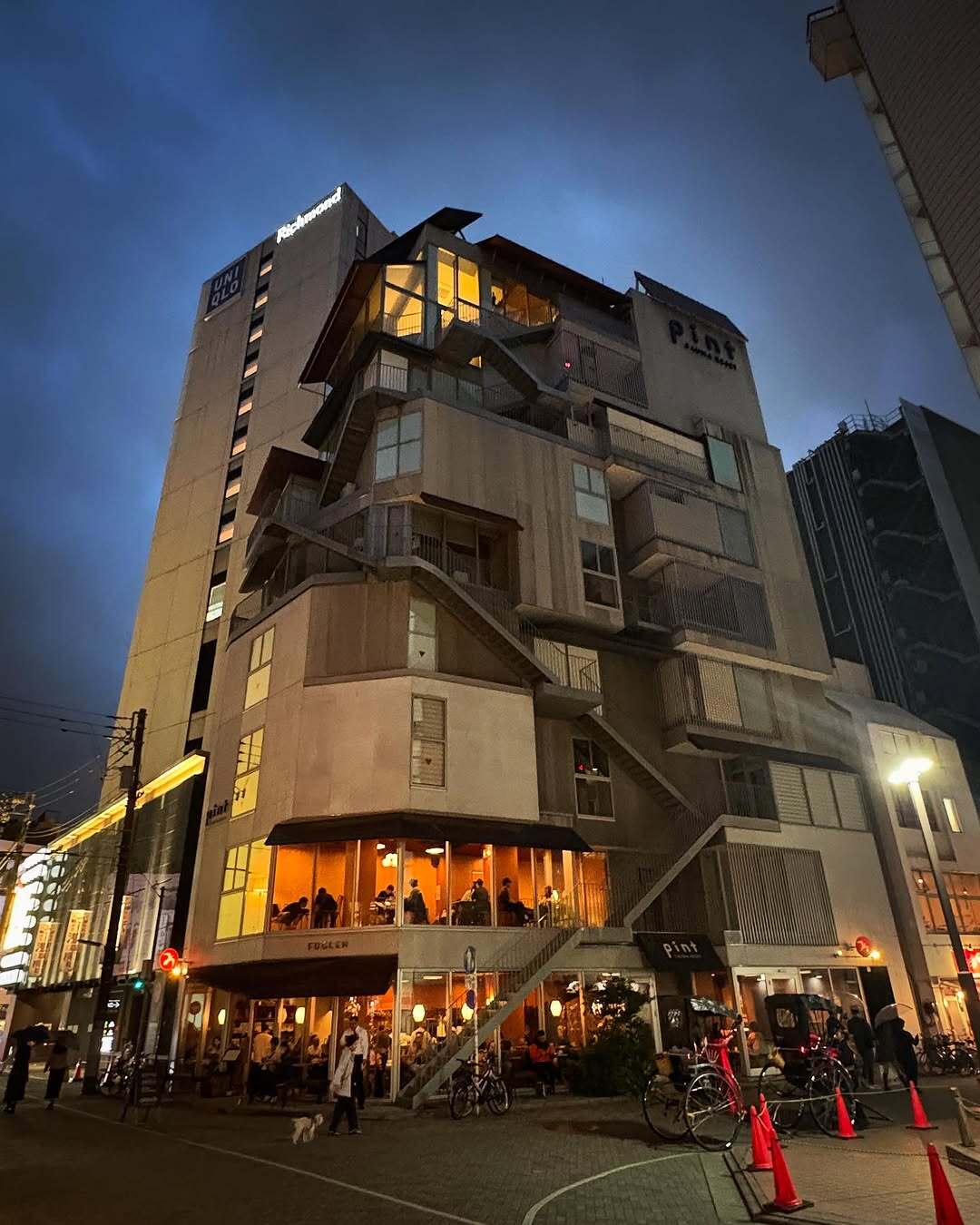 نمای ساختمان ناین آورز آساکوسا در توکیو که طی سال‌های ۲۰۱۸ تا ۲۰۲۵ از هتل کپسولی به برج سونا تغییر کاربری داده و اکنون تنها کافه نروژی FUGLEN در طبقه همکف آن فعال است؛ تصویری مرتبط با معماری و تغییرات کاربری بنا در منطقه آساکوسا.