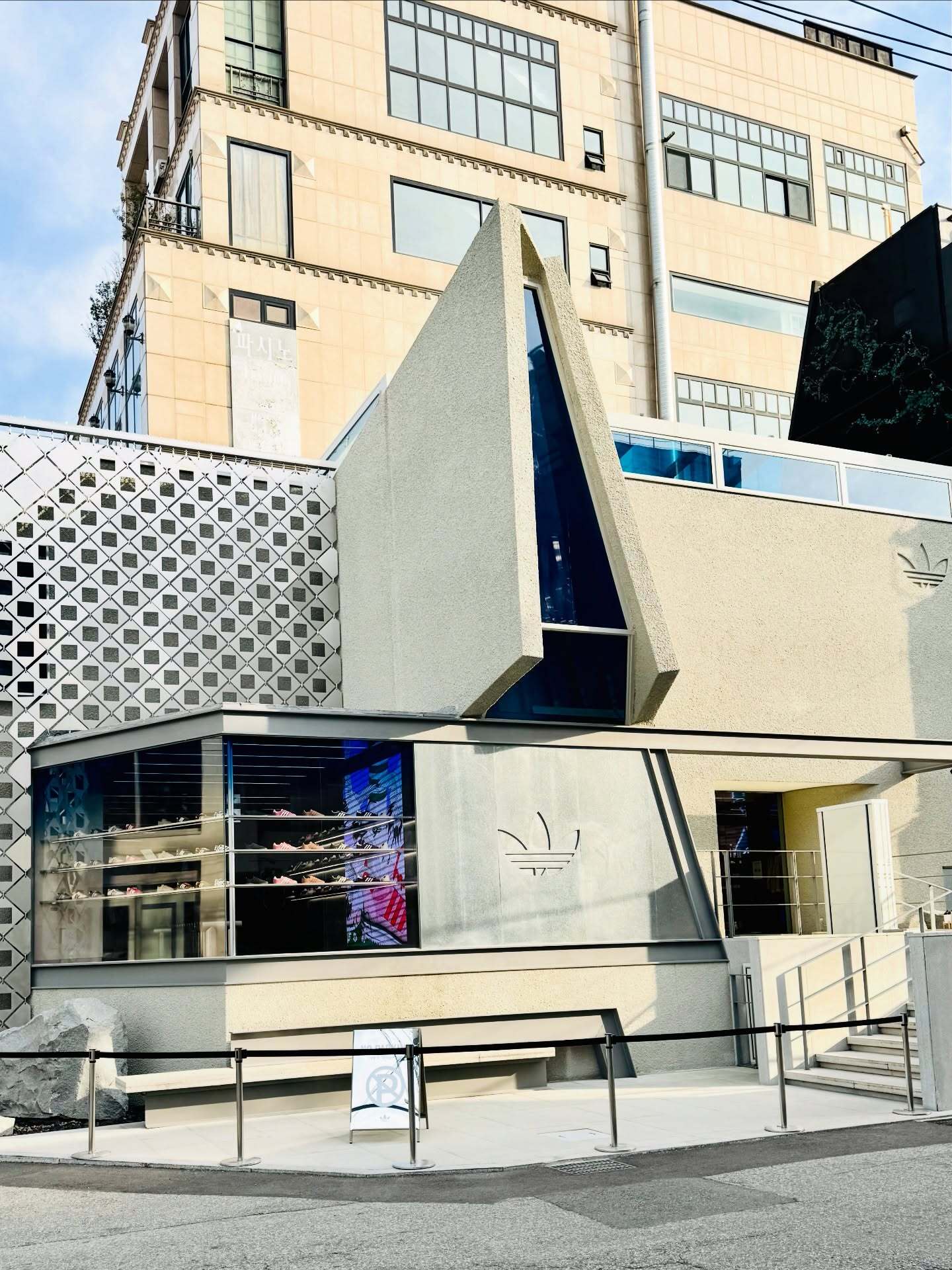 تصویری از نمای خارجی فروشگاه پرچم‌دار آدیداس اُریجینالز دوسان (Adidas Originals Flagship Dosan) در سئول کره جنوبی، ساختمانی که در اصل یک خانه مسکونی بوده و اکنون تحت بازسازی برای تبدیل کاربری به یک فضای تجاری بزرگ و مدرن برای عرضه محصولات آدیداس قرار گرفته است.