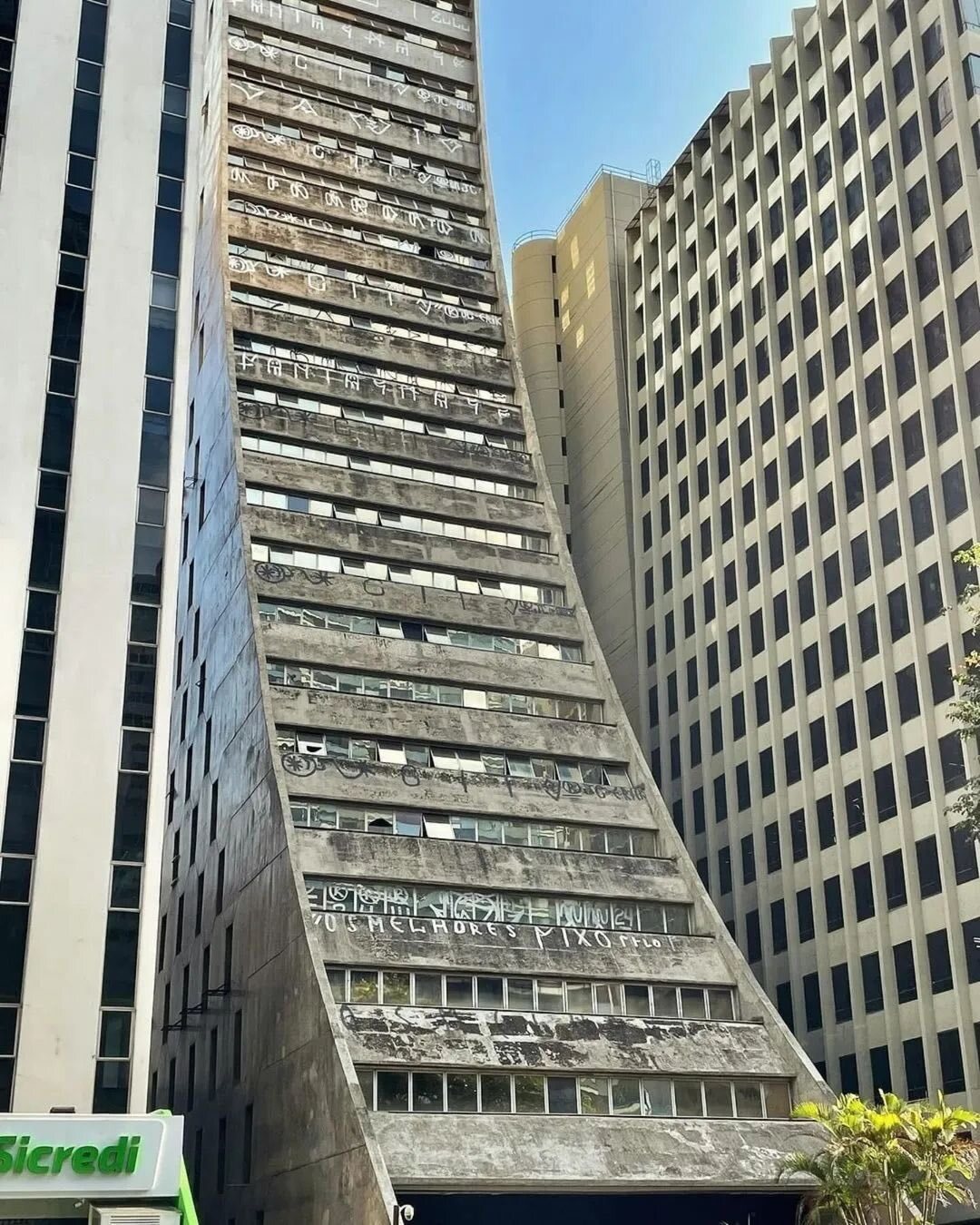 تصویری از یکی از بناهای نمادین سبک بروتالیسم در برزیل، احتمالاً ساختمان دانشکده معماری و شهرسازی دانشگاه سائوپائولو یا ساختمان کوپان، که سازه‌ای عظیم از بتن خام و سفید بوده و نشان‌دهنده نقش این سبک در توسعه ساختمان‌های عمومی و دانشگاهی در برزیل است.