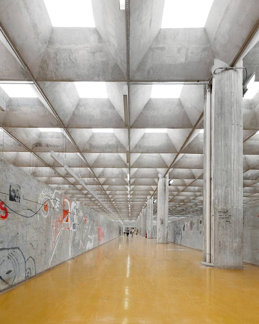 تصویری از یکی از بناهای نمادین سبک بروتالیسم در برزیل، احتمالاً ساختمان دانشکده معماری و شهرسازی دانشگاه سائوپائولو یا ساختمان کوپان، که سازه‌ای عظیم از بتن خام و سفید بوده و نشان‌دهنده نقش این سبک در توسعه ساختمان‌های عمومی و دانشگاهی در برزیل است.