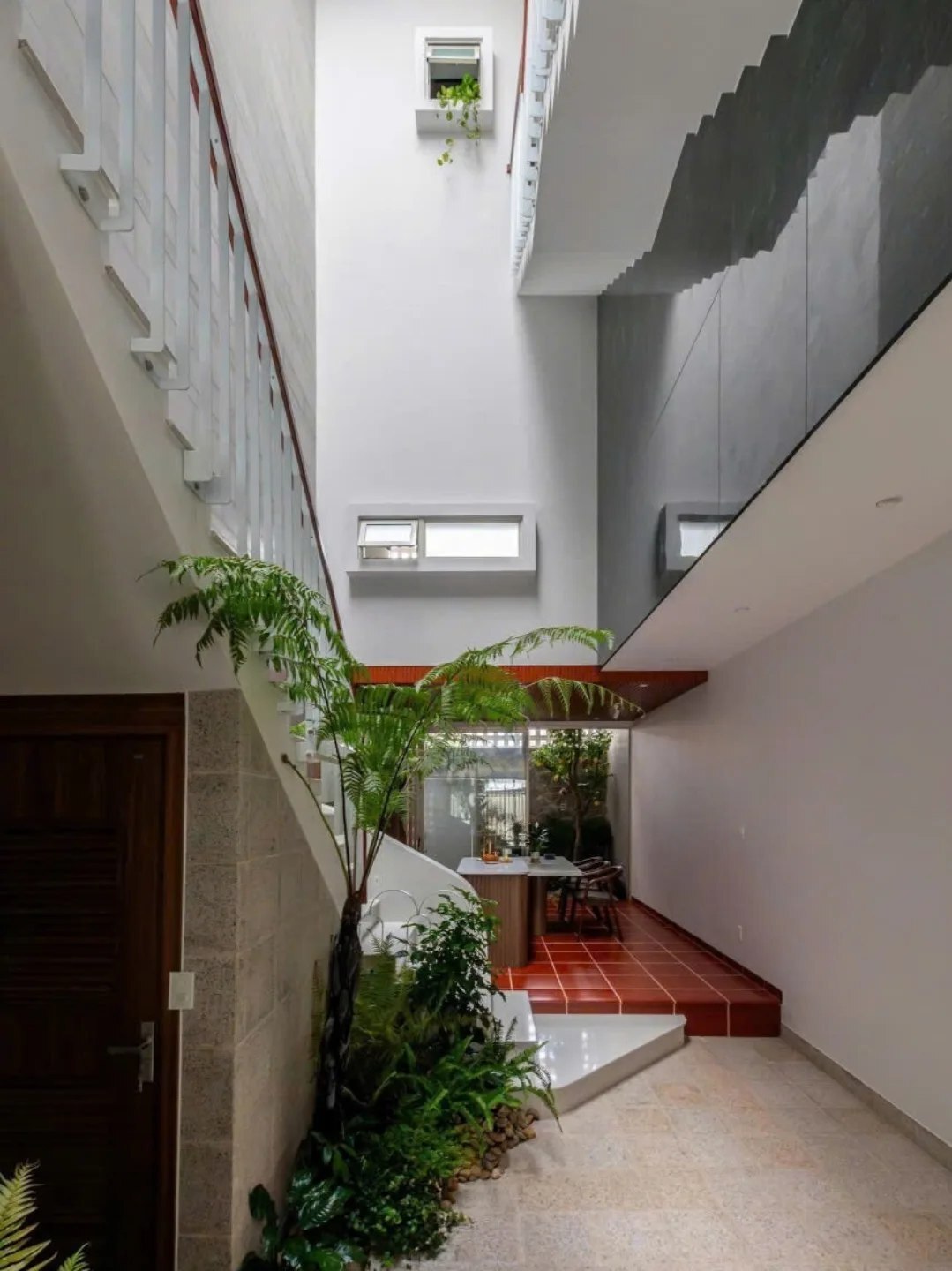 نمای خارجی و داخلی خانه چهار طبقه «شهر غربی» (Casa Cidade do Oeste) در ویتنام با مساحت ۹۰ متر مربع، که طراحی آن شامل نمای ساده، لایه‌های انبوه گیاهی برای حفظ حریم خصوصی، و فضاهای داخلی پلان باز با نورگیر مرکزی برای ایجاد محیطی آرام و روشن است.