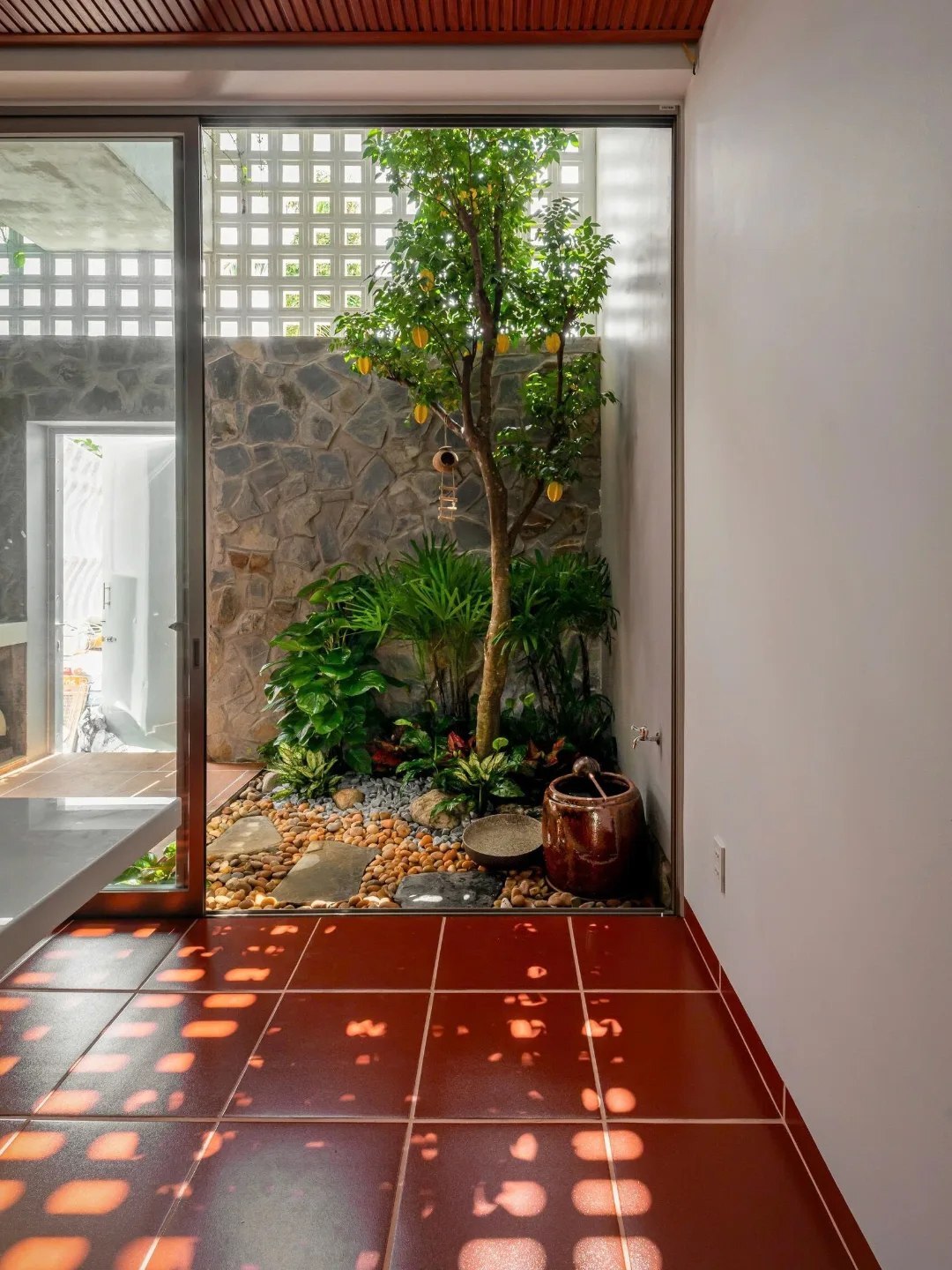 نمای خارجی و داخلی خانه چهار طبقه «شهر غربی» (Casa Cidade do Oeste) در ویتنام با مساحت ۹۰ متر مربع، که طراحی آن شامل نمای ساده، لایه‌های انبوه گیاهی برای حفظ حریم خصوصی، و فضاهای داخلی پلان باز با نورگیر مرکزی برای ایجاد محیطی آرام و روشن است.