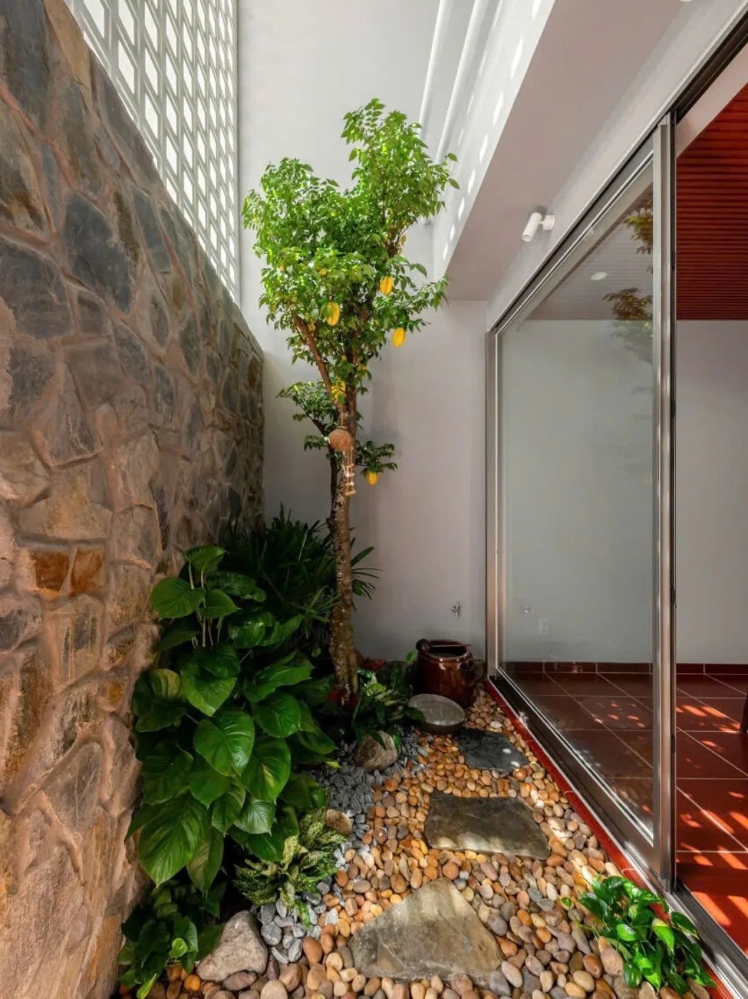 نمای خارجی و داخلی خانه چهار طبقه «شهر غربی» (Casa Cidade do Oeste) در ویتنام با مساحت ۹۰ متر مربع، که طراحی آن شامل نمای ساده، لایه‌های انبوه گیاهی برای حفظ حریم خصوصی، و فضاهای داخلی پلان باز با نورگیر مرکزی برای ایجاد محیطی آرام و روشن است.