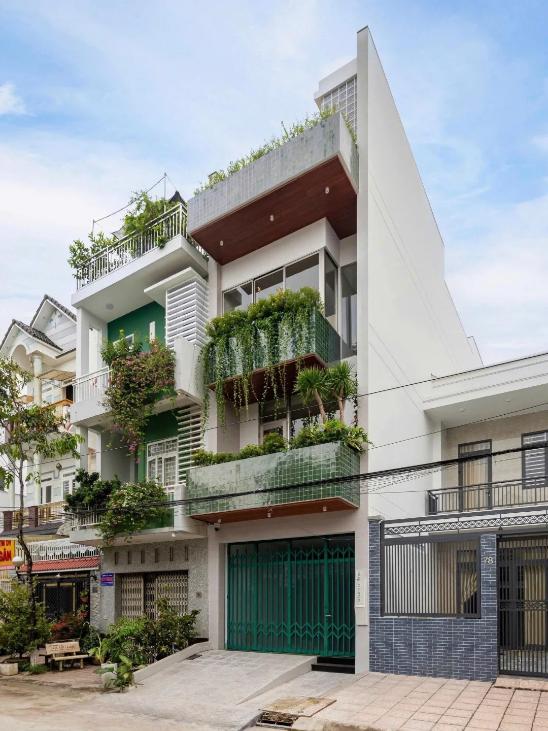 نمای خارجی و داخلی خانه چهار طبقه «شهر غربی» (Casa Cidade do Oeste) در ویتنام با مساحت ۹۰ متر مربع، که طراحی آن شامل نمای ساده، لایه‌های انبوه گیاهی برای حفظ حریم خصوصی، و فضاهای داخلی پلان باز با نورگیر مرکزی برای ایجاد محیطی آرام و روشن است.