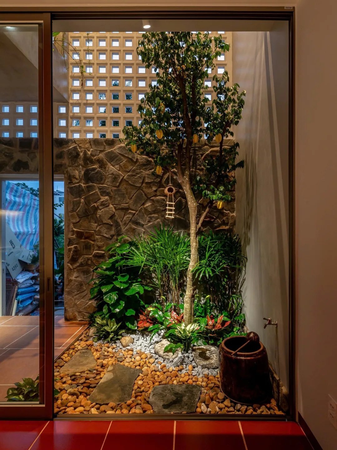 نمای خارجی و داخلی خانه چهار طبقه «شهر غربی» (Casa Cidade do Oeste) در ویتنام با مساحت ۹۰ متر مربع، که طراحی آن شامل نمای ساده، لایه‌های انبوه گیاهی برای حفظ حریم خصوصی، و فضاهای داخلی پلان باز با نورگیر مرکزی برای ایجاد محیطی آرام و روشن است.