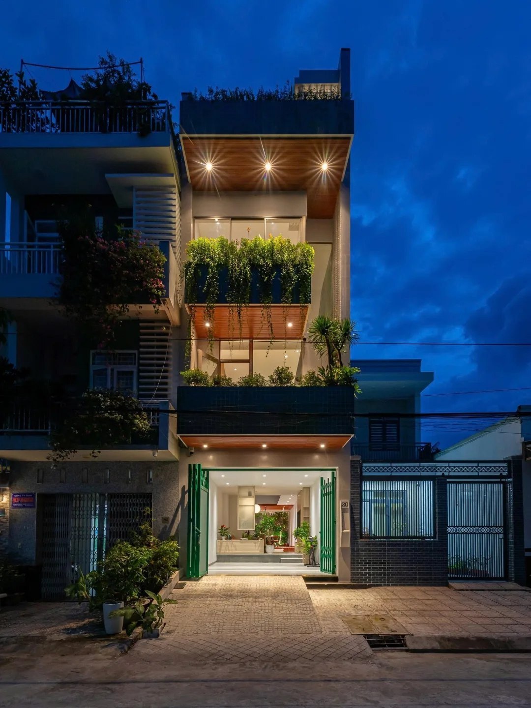 نمای خارجی و داخلی خانه چهار طبقه «شهر غربی» (Casa Cidade do Oeste) در ویتنام با مساحت ۹۰ متر مربع، که طراحی آن شامل نمای ساده، لایه‌های انبوه گیاهی برای حفظ حریم خصوصی، و فضاهای داخلی پلان باز با نورگیر مرکزی برای ایجاد محیطی آرام و روشن است.