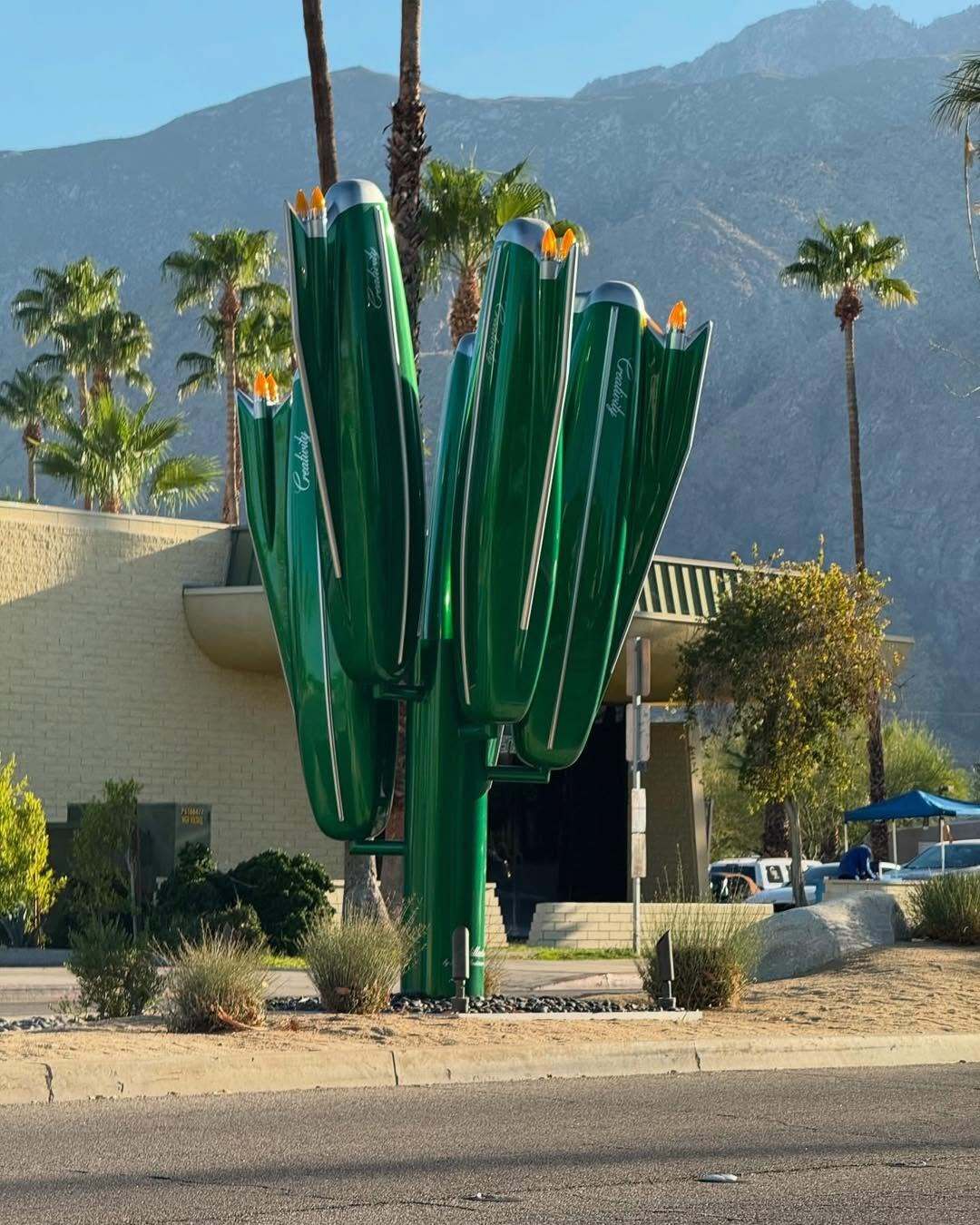 مجسمه بزرگ و سبزرنگ به شکل کاکتوس که از باله‌های عقب (Tailfins) خودروهای کلاسیک کادیلاک دهه ۱۹۵۰ و ۱۹۶۰ الهام گرفته شده، و کلمه Creativity (خلاقیت) روی بدنه آن نوشته شده است؛ این اثر هنری در یک محیط بیابانی با درختان نخل و کوه‌های پس‌زمینه قرار دارد.