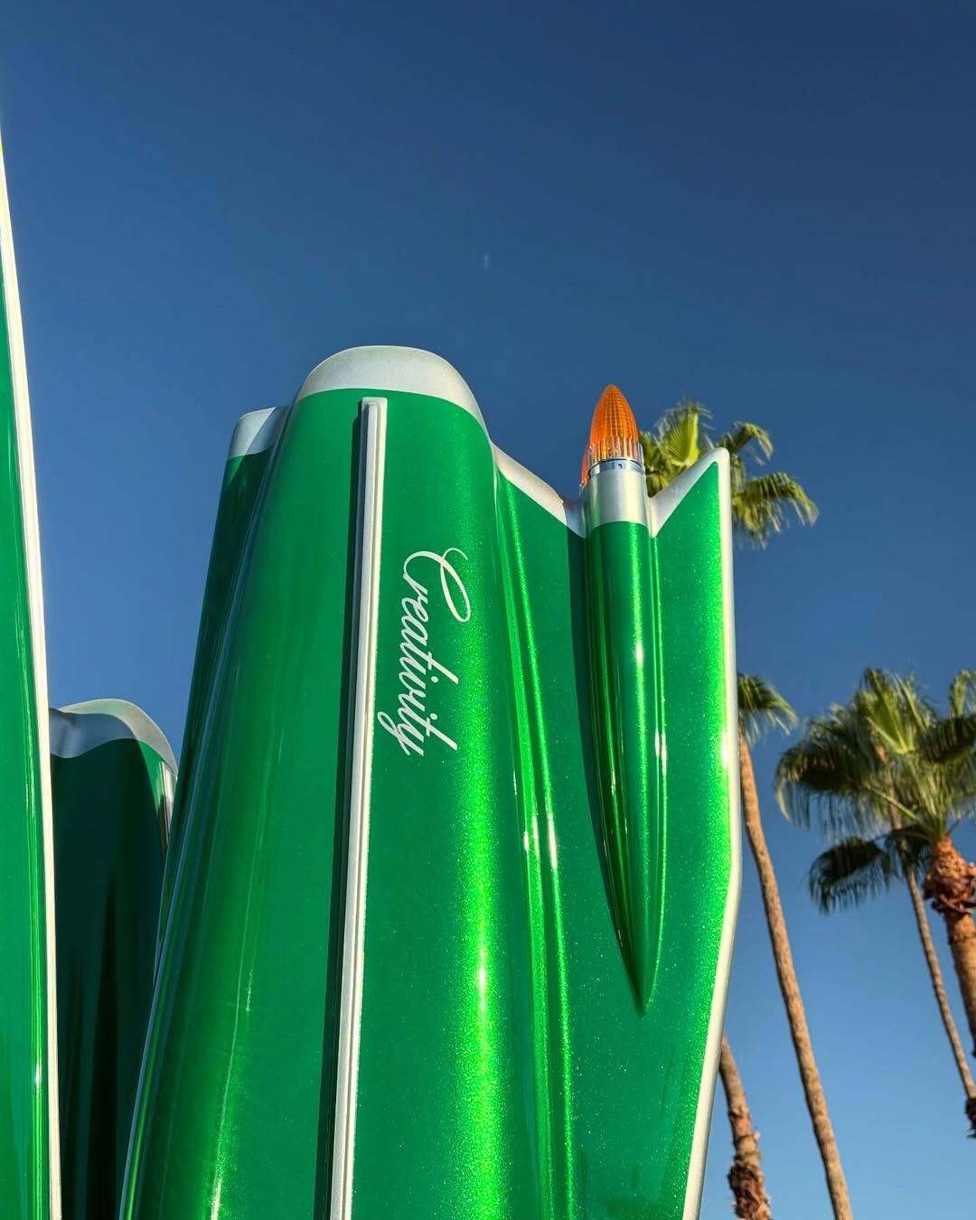 مجسمه بزرگ و سبزرنگ به شکل کاکتوس که از باله‌های عقب (Tailfins) خودروهای کلاسیک کادیلاک دهه ۱۹۵۰ و ۱۹۶۰ الهام گرفته شده، و کلمه Creativity (خلاقیت) روی بدنه آن نوشته شده است؛ این اثر هنری در یک محیط بیابانی با درختان نخل و کوه‌های پس‌زمینه قرار دارد.