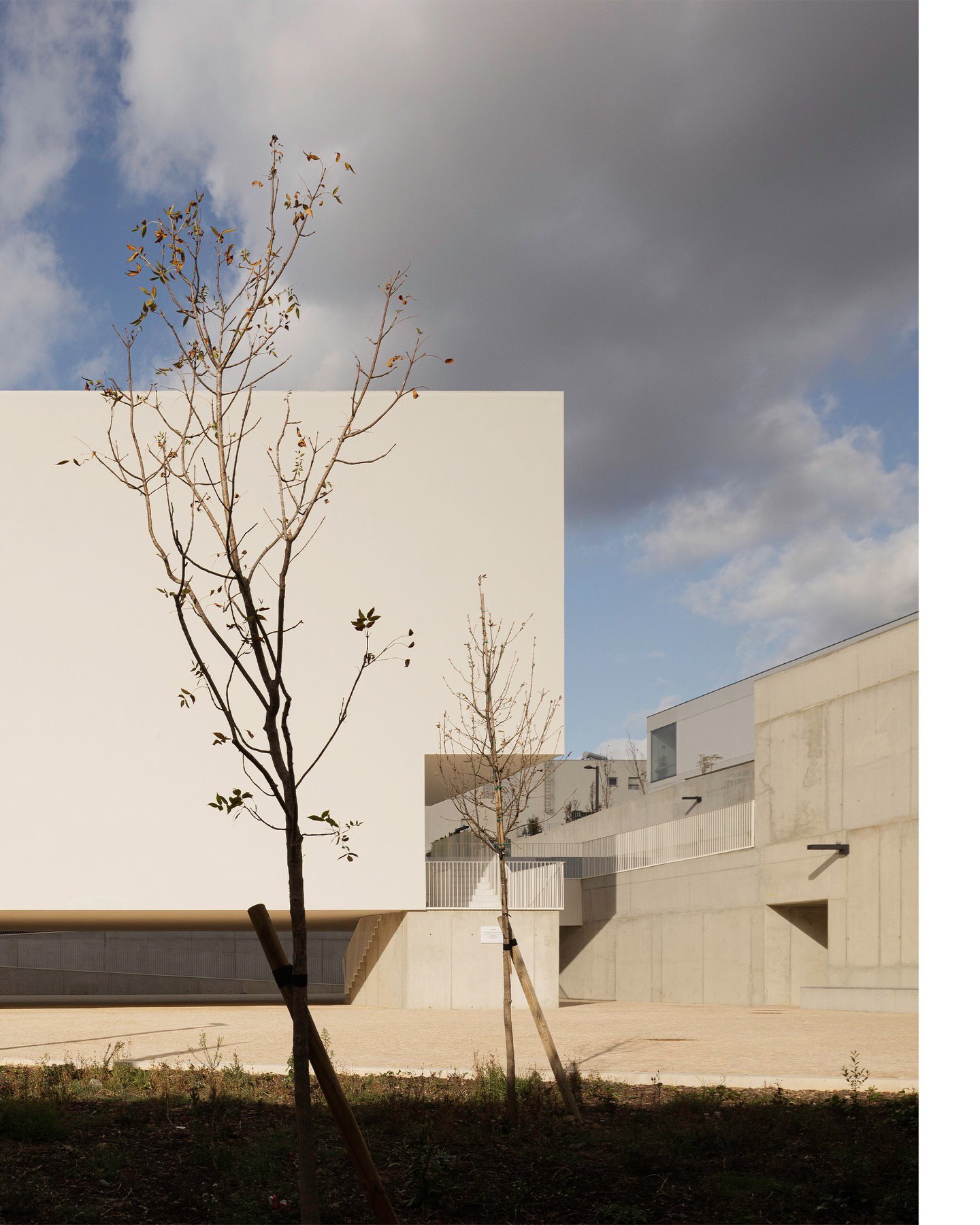 تصویری از نمای داخلی یا بیرونی کلیسای سائو ژوزه دابوآویستا (The Church of São José da Boavista) در پرتغال، با معماری مینیمالیستی نرم و مدرن، که توسط آتلیه بوگیو و ماتوس گامیرو آرکیتکتوس طراحی شده است. تأکید این تصویر بر خطوط تمیز، حجم‌های هندسی ساده و نور