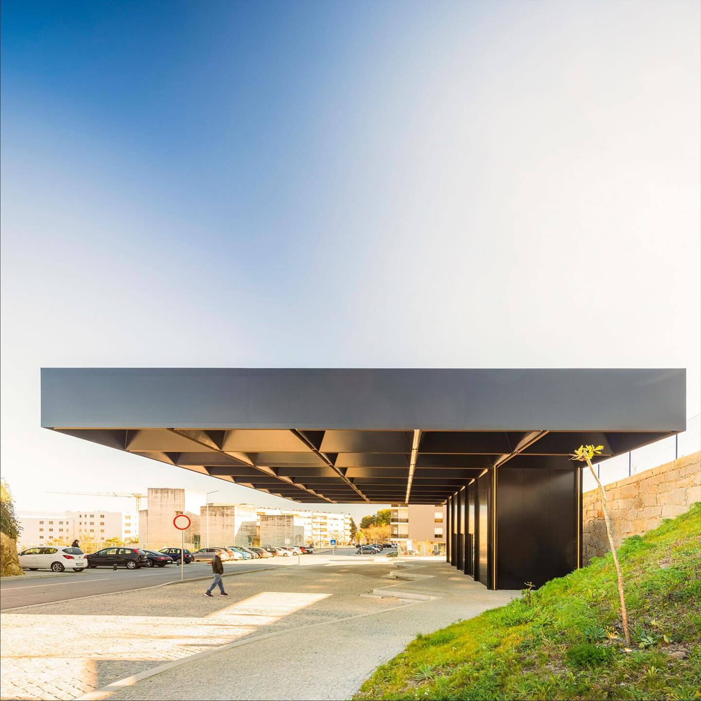 تصویری از نمای خارجی مرکز چندوجهی (Intermodal Center) در لوزادا، واقع در شمال شرقی پورتو پرتغال، که توسط شرکت معماری Spaceworkers طراحی شده است. این ساختمان با حجم‌های هندسی خاص و مدرن و استفاده از مصالح سفید یا روشن، به عنوان یک نشانه‌ی شهری و قطب جدید ف