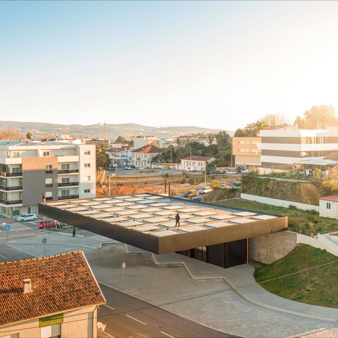 تصویری از نمای خارجی مرکز چندوجهی (Intermodal Center) در لوزادا، واقع در شمال شرقی پورتو پرتغال، که توسط شرکت معماری Spaceworkers طراحی شده است. این ساختمان با حجم‌های هندسی خاص و مدرن و استفاده از مصالح سفید یا روشن، به عنوان یک نشانه‌ی شهری و قطب جدید ف