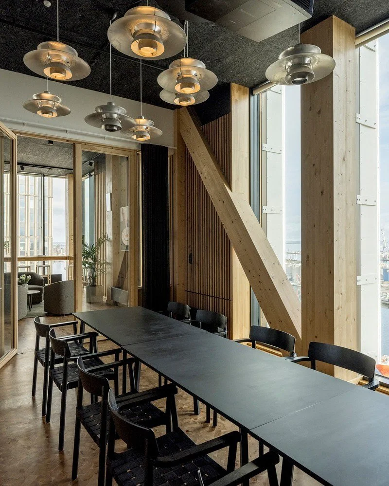 تصویر نمای خارجی و مدرن ساختمان TRÆ (ترا) در بندر آرهوس، دانمارک، که با سیستم سازه‌ای چوبی-هیبریدی و پوشش نمای آلومینیوم بازیافتی توسط Lendager Arkitekter به سبک معماری چرخه‌محور طراحی شده است.