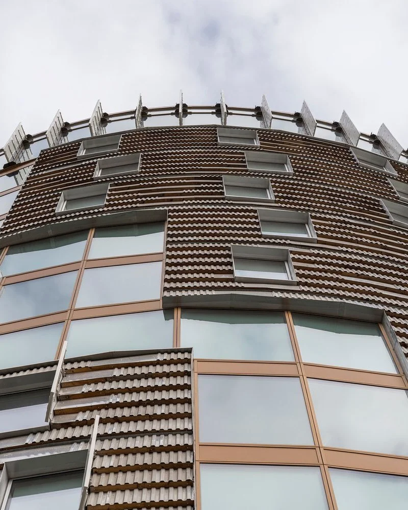 تصویر نمای خارجی و مدرن ساختمان TRÆ (ترا) در بندر آرهوس، دانمارک، که با سیستم سازه‌ای چوبی-هیبریدی و پوشش نمای آلومینیوم بازیافتی توسط Lendager Arkitekter به سبک معماری چرخه‌محور طراحی شده است.