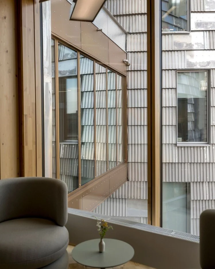 تصویر نمای خارجی و مدرن ساختمان TRÆ (ترا) در بندر آرهوس، دانمارک، که با سیستم سازه‌ای چوبی-هیبریدی و پوشش نمای آلومینیوم بازیافتی توسط Lendager Arkitekter به سبک معماری چرخه‌محور طراحی شده است.