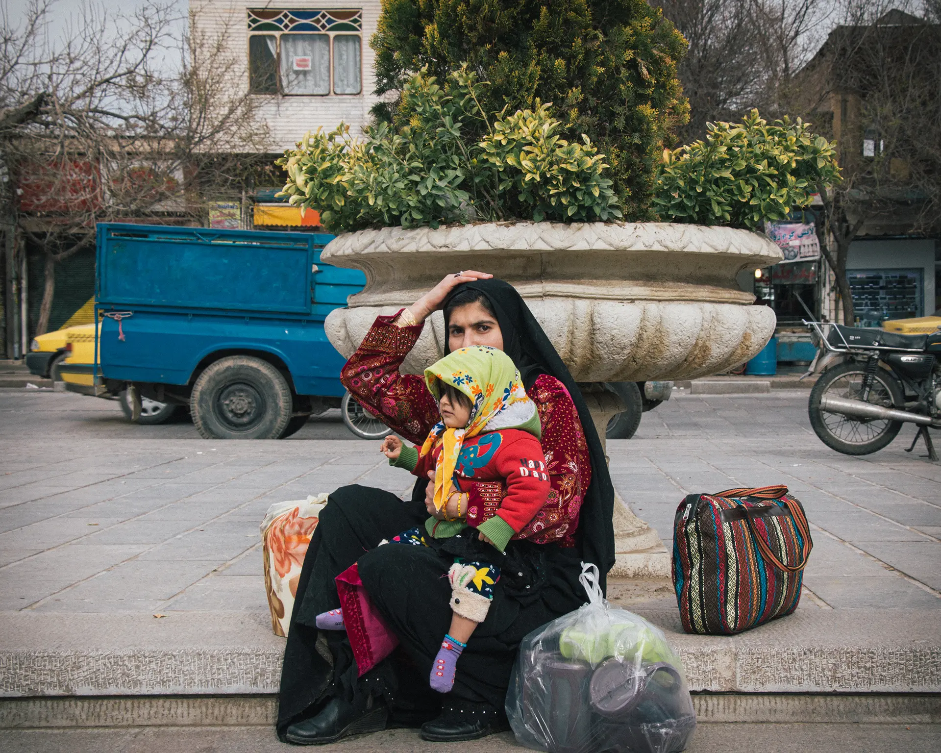 یک مادر و کودکش نشسته کنار خیابان
