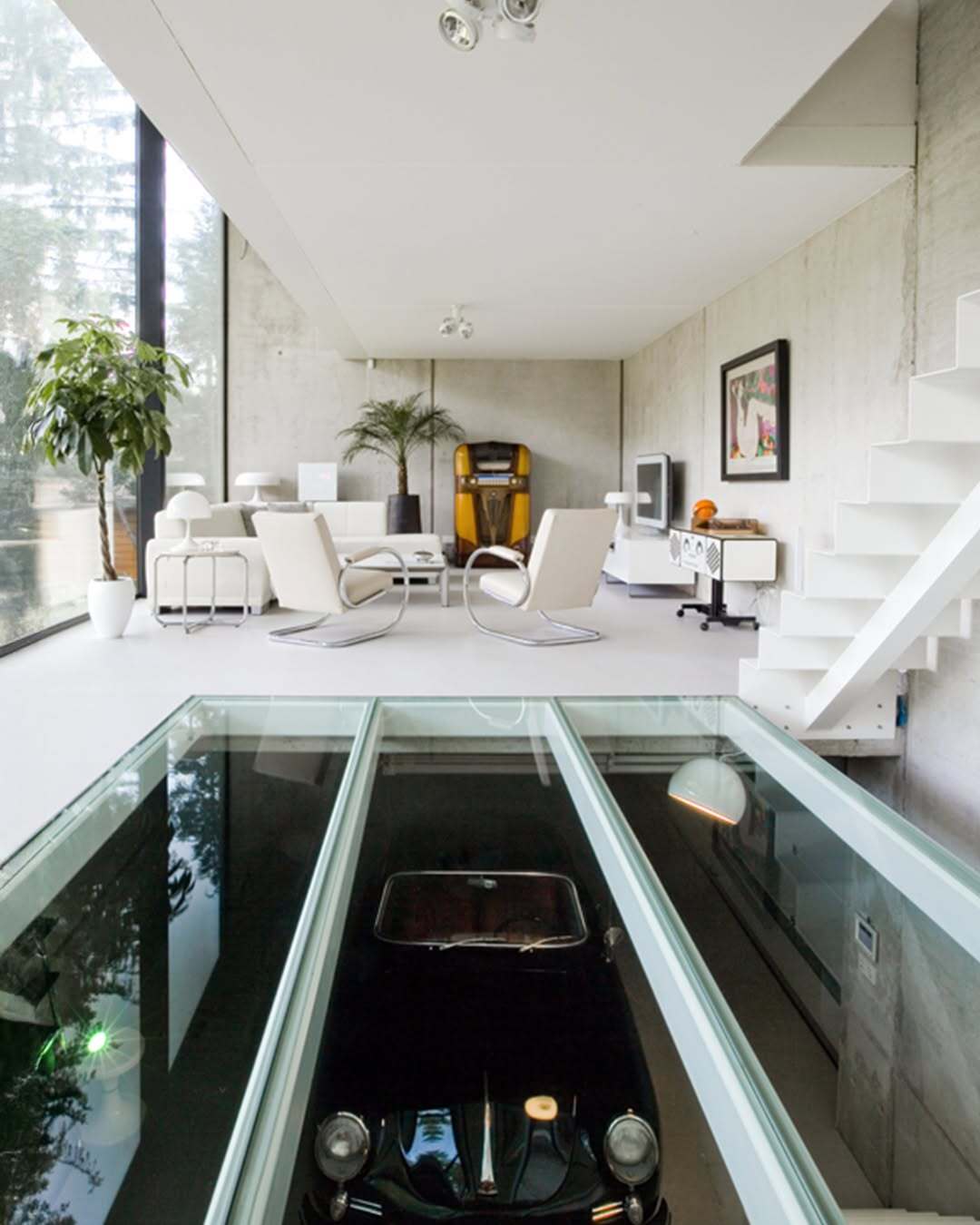 تصویر معماری مدرن و خطی یک خانه در بلژیک که نمای جلویی آن توسط بتن مستحکم پوشیده شده است، اما نمای پشتی کاملاً شیشه‌ای بوده و چشم‌اندازی بی‌نظیر به کانال آبی «کِمپیشه» را به نمایش می‌گذارد.