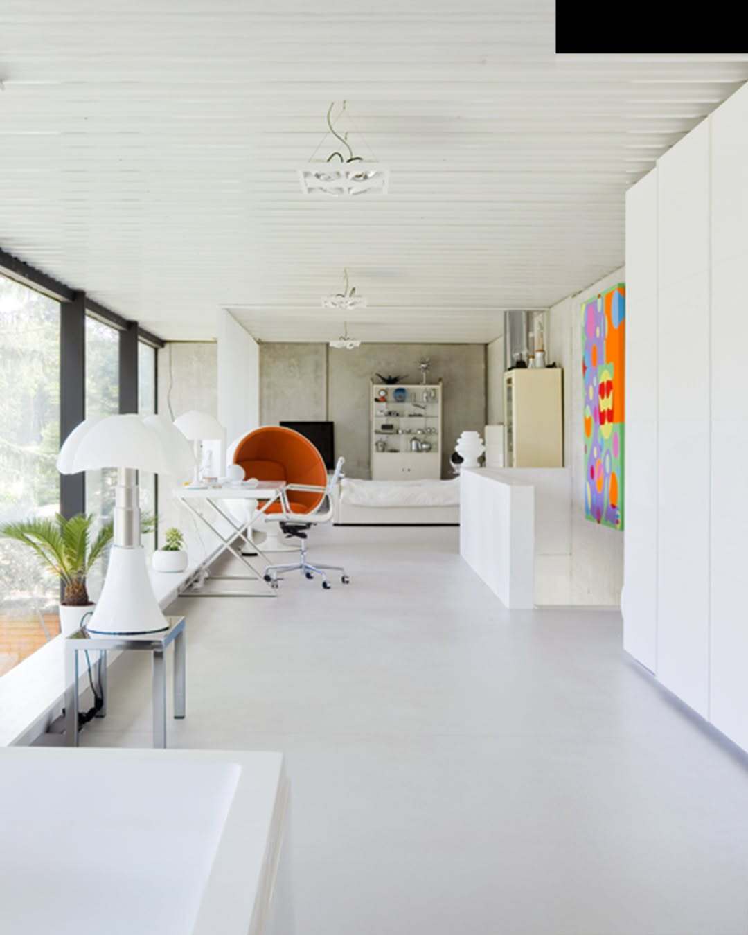 تصویر معماری مدرن و خطی یک خانه در بلژیک که نمای جلویی آن توسط بتن مستحکم پوشیده شده است، اما نمای پشتی کاملاً شیشه‌ای بوده و چشم‌اندازی بی‌نظیر به کانال آبی «کِمپیشه» را به نمایش می‌گذارد.