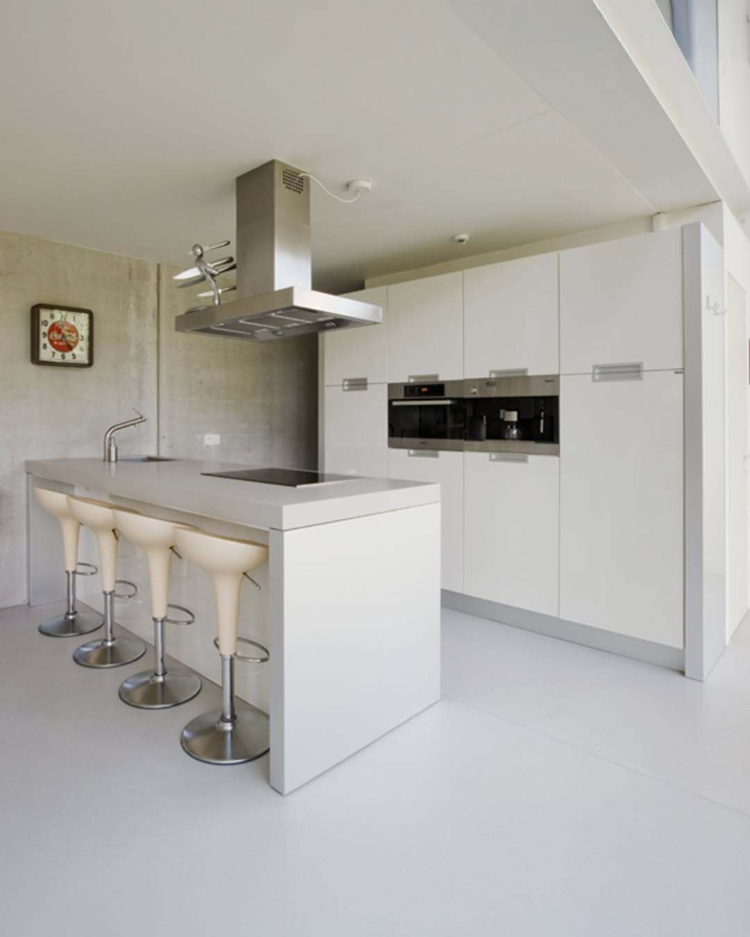 تصویر معماری مدرن و خطی یک خانه در بلژیک که نمای جلویی آن توسط بتن مستحکم پوشیده شده است، اما نمای پشتی کاملاً شیشه‌ای بوده و چشم‌اندازی بی‌نظیر به کانال آبی «کِمپیشه» را به نمایش می‌گذارد.