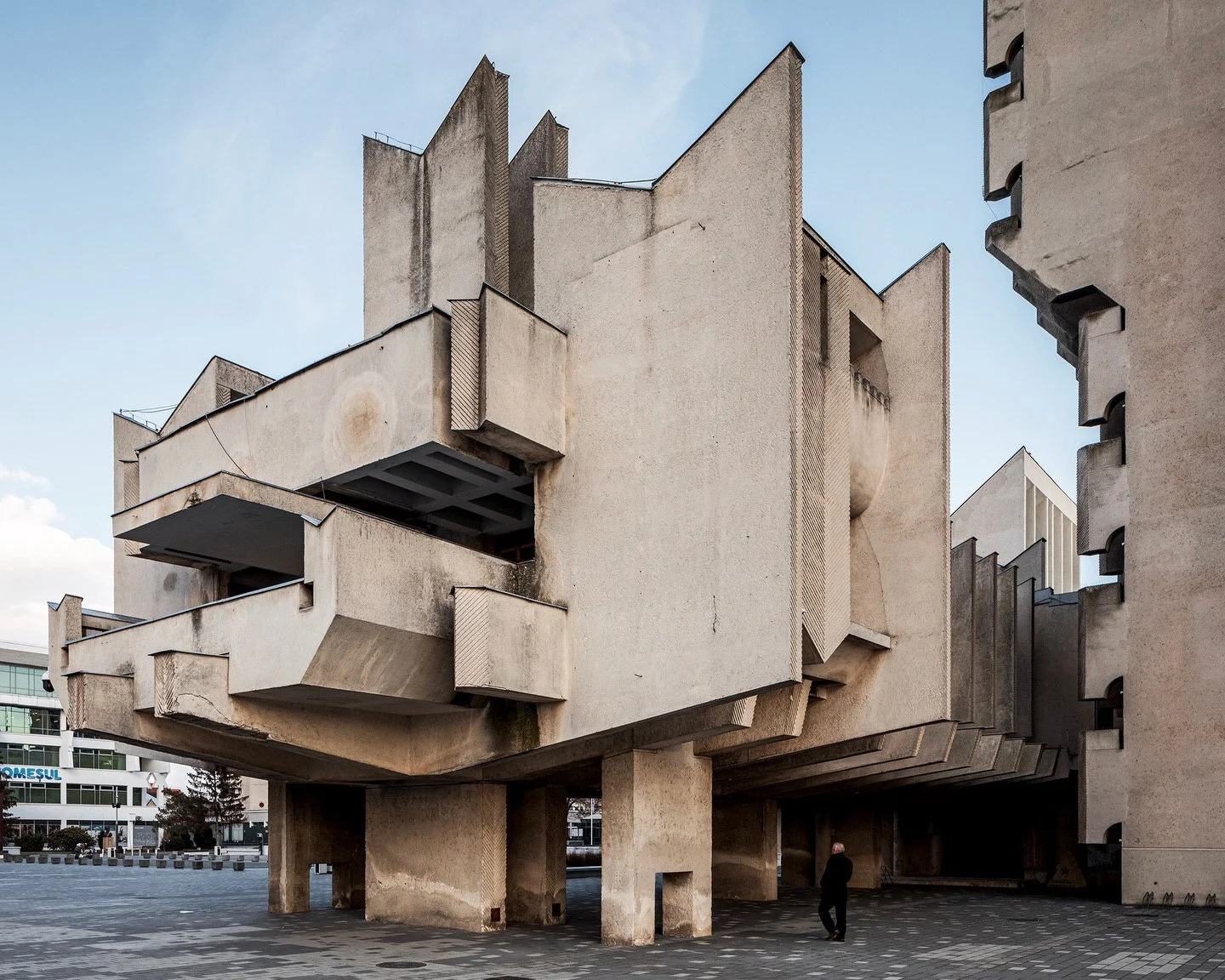 تصویر تمامنمای کاخ اداری (Administrative Palace) در ساتو ماره، رومانی؛ این بنای بزرگ که توسط نیکولای پورومبسکو در سالهای ۱۹۷۲ تا ۱۹۸۴ طراحی شده، نمونه برجستهای از معماری بروتالیسم سوسیالیستی با نمای بتنی، خطوط سنگین و سبک مدرن است. تصویر تمامنمای کاخ اداری (Administrative Palace) در ساتو ماره، رومانی؛ این بنای بزرگ که توسط نیکولای پورومبسکو در سالهای ۱۹۷۲ تا ۱۹۸۴ طراحی شده، نمونه برجستهای از معماری بروتالیسم سوسیالیستی با نمای بتنی، خطوط سنگین و سبک مدرن است.