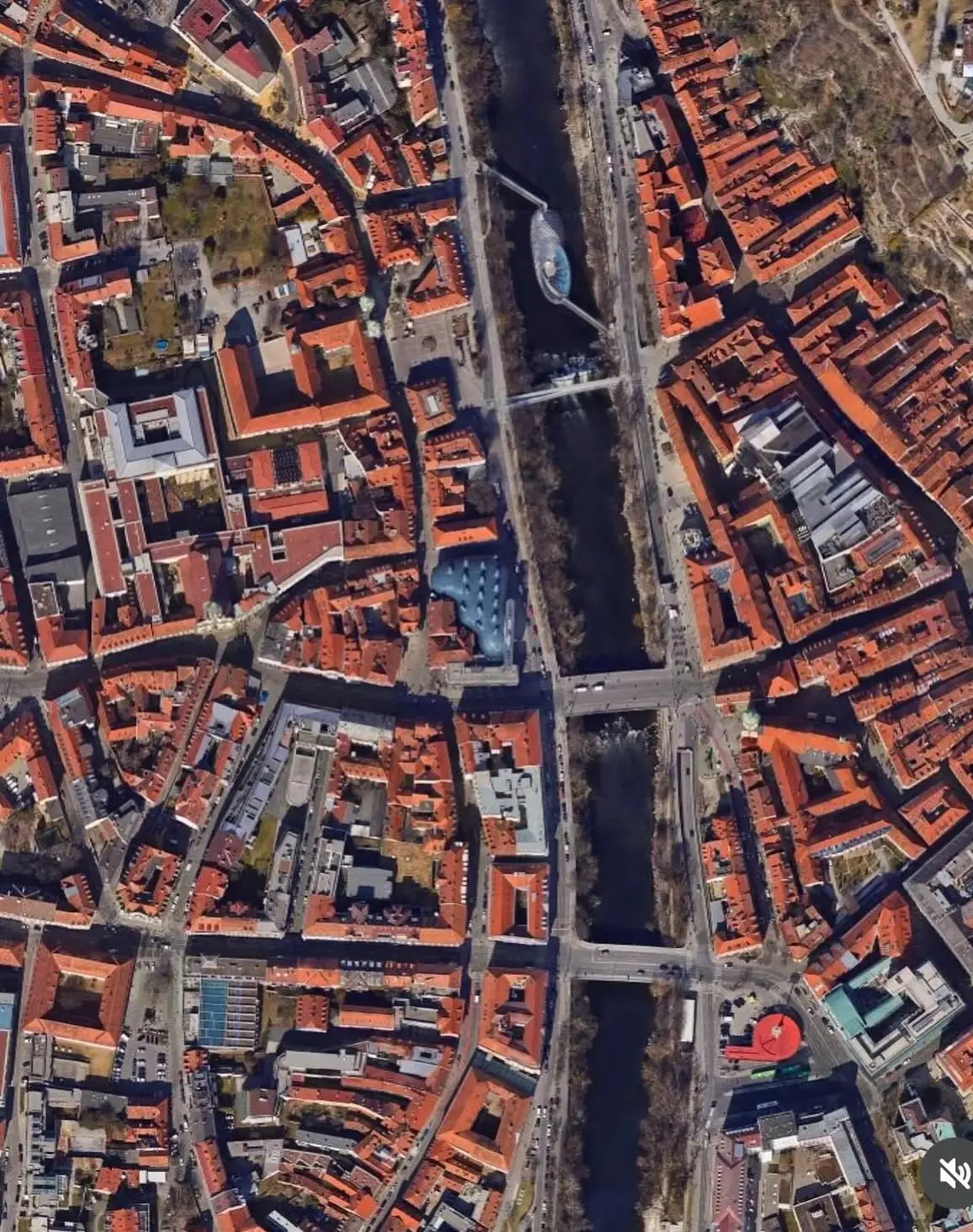 تصویری از نمای خارجی ساختمان موزه هنر کونست‌هاوس (Kunsthaus) در گراتس اتریش، که ساختار ارگانیک و غیرمعمول آن شبیه به یک موجود زنده با پوسته آبی رنگ است و به عنوان یک نماد معماری مدرن و «بیگانه دوست» طراحی شده توسط کولین فورنیر و پیتر کوک شناخته می‌شود.