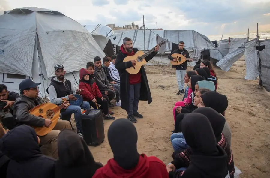 معلم موسیقی فلسطینی در اردوگاهی در نوار غزه  برای آوارگان جنگ، ترانه می خواند./ آناتولی
