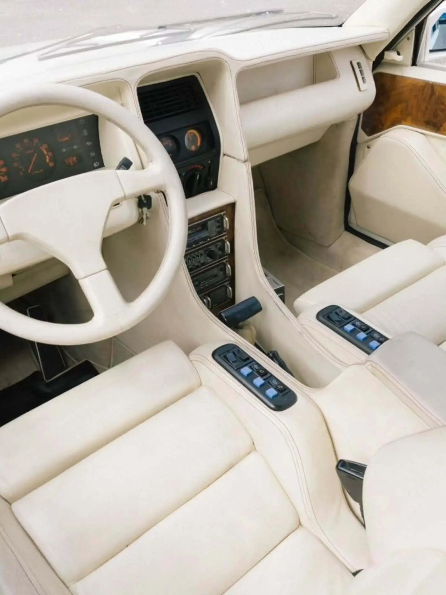 تصویر خودروی کلاسیک و نایاب اسبارو سوپر فایو (Sbarro Super Five) مدل ۱۹۸۵ با بدنه پهن سفید و چراغ‌های جلو چهارگانه در یک منظره کوهستانی.