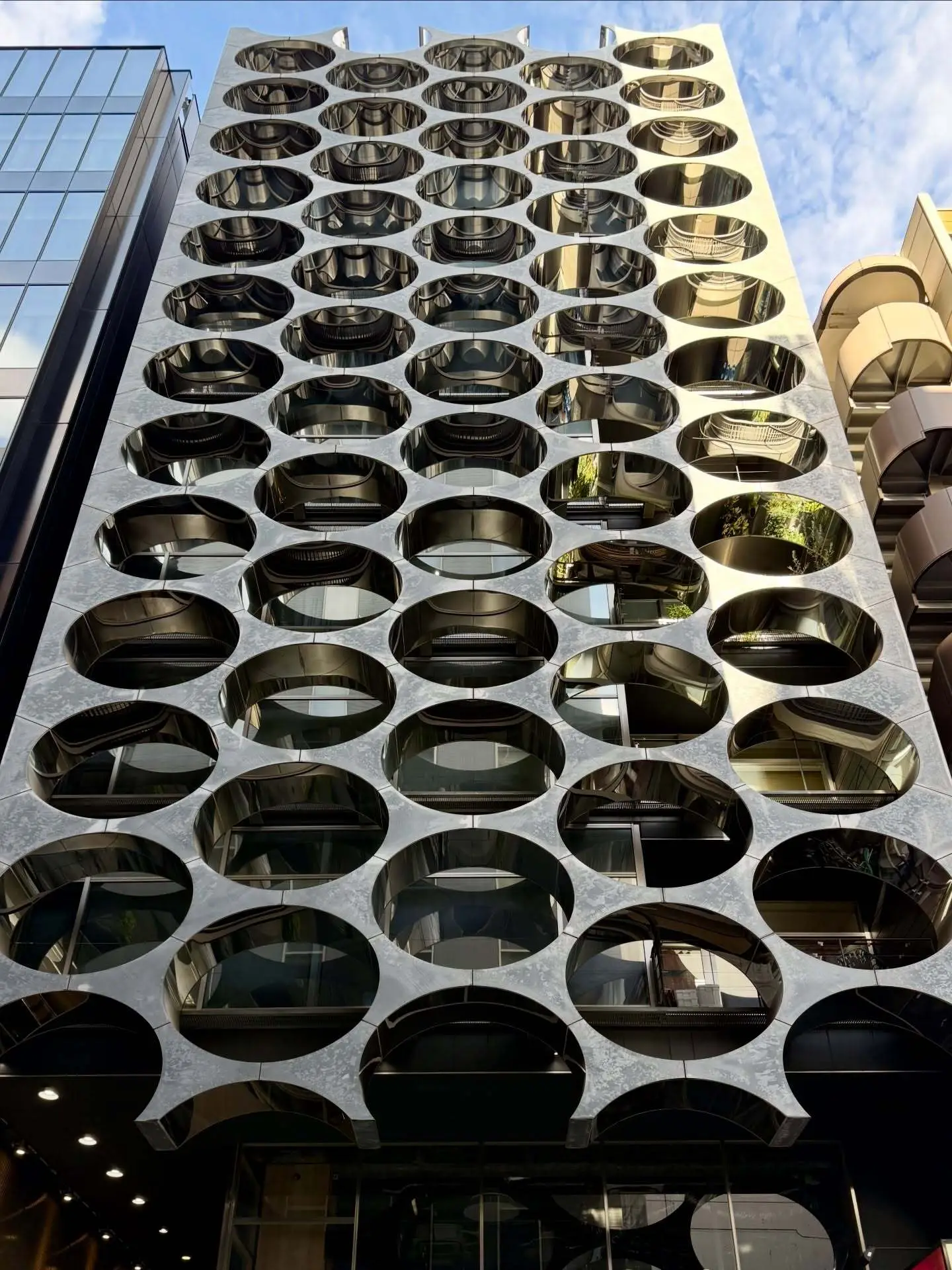 نمای خارجی ساختمان آلفا ماتریکس در توکیو اثر تاکتو شیموهیگوشی، با قاب‌های فلزی مستطیلی و پنل‌های شیشه‌ای مدرن در منطقه گینزا.