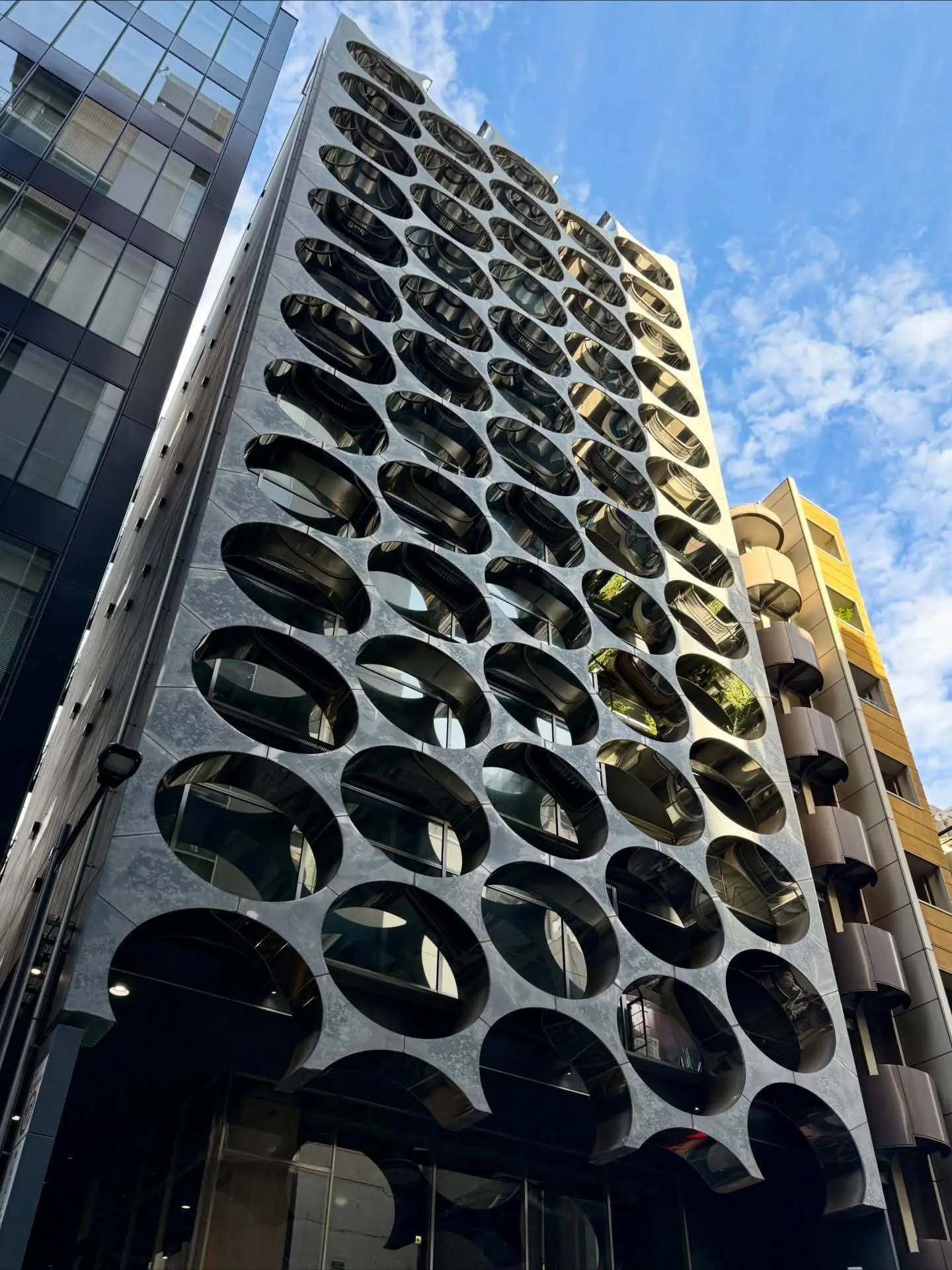 نمای خارجی ساختمان آلفا ماتریکس در توکیو اثر تاکتو شیموهیگوشی، با قاب‌های فلزی مستطیلی و پنل‌های شیشه‌ای مدرن در منطقه گینزا.