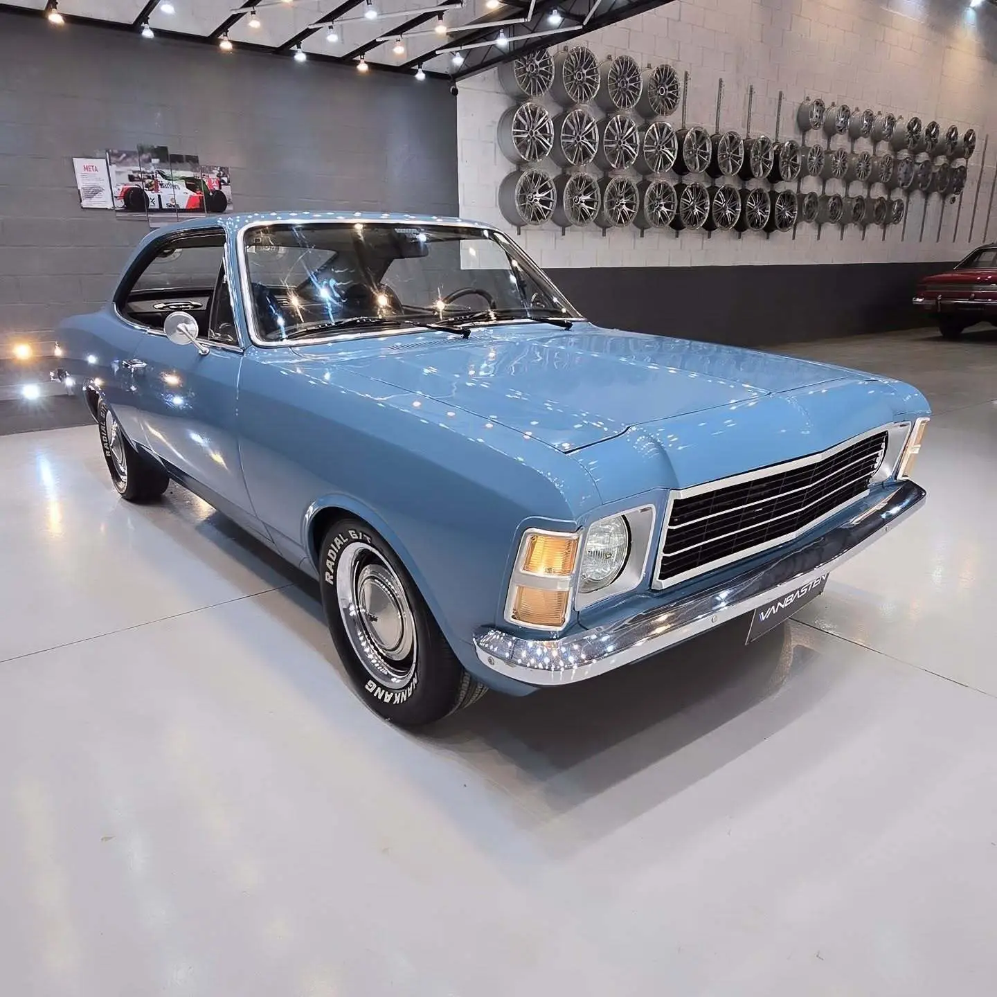 نمای کناری و موتور ارتقایافته شورولت اوپالا ۲۵۰۰ مدل ۱۹۷۶ توربو به رنگ سفید با رینگ‌های کلاسیک و کیت بدنه فابریک در وضعیت نمایشگاهی.