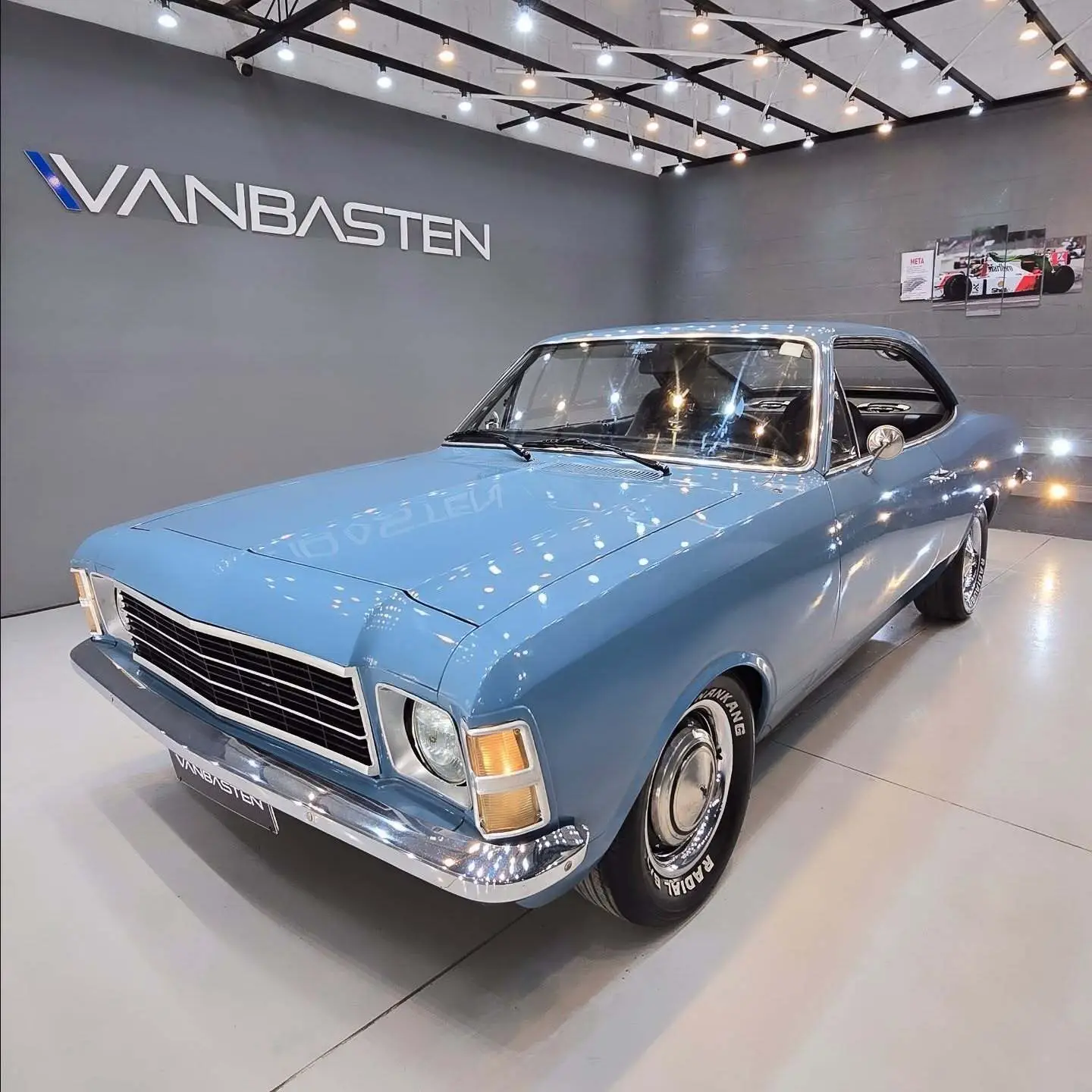 نمای کناری و موتور ارتقایافته شورولت اوپالا ۲۵۰۰ مدل ۱۹۷۶ توربو به رنگ سفید با رینگ‌های کلاسیک و کیت بدنه فابریک در وضعیت نمایشگاهی.