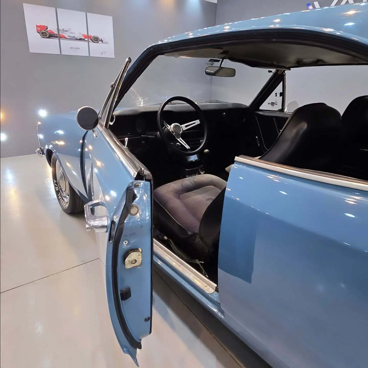 نمای کناری و موتور ارتقایافته شورولت اوپالا ۲۵۰۰ مدل ۱۹۷۶ توربو به رنگ سفید با رینگ‌های کلاسیک و کیت بدنه فابریک در وضعیت نمایشگاهی.