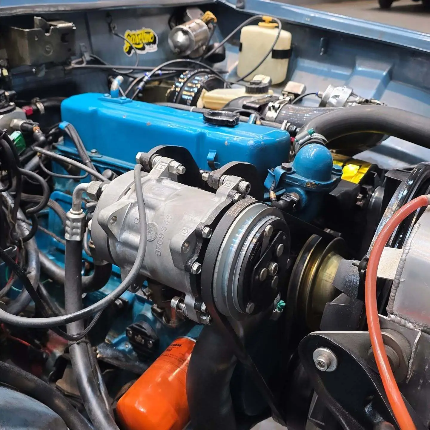 نمای کناری و موتور ارتقایافته شورولت اوپالا ۲۵۰۰ مدل ۱۹۷۶ توربو به رنگ سفید با رینگ‌های کلاسیک و کیت بدنه فابریک در وضعیت نمایشگاهی.