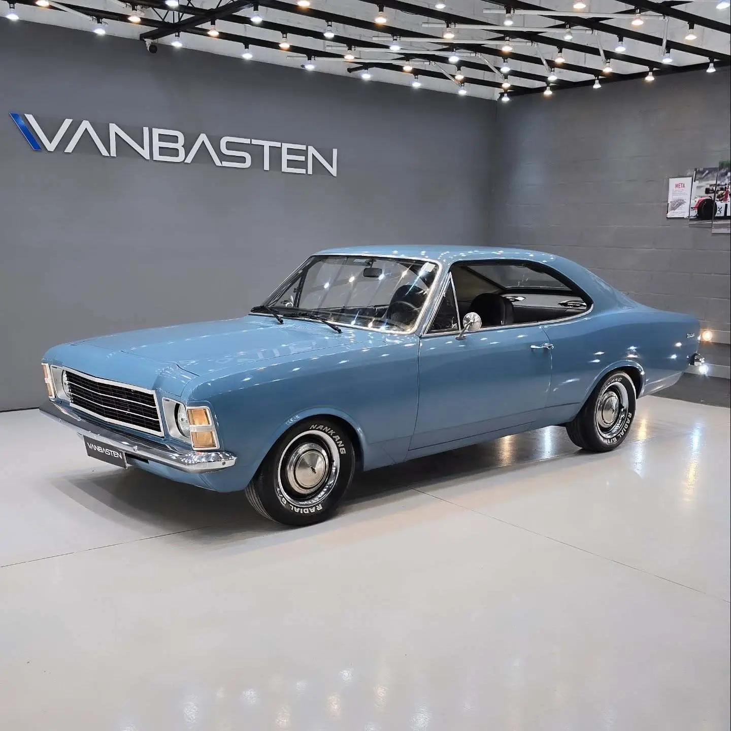 نمای کناری و موتور ارتقایافته شورولت اوپالا ۲۵۰۰ مدل ۱۹۷۶ توربو به رنگ سفید با رینگ‌های کلاسیک و کیت بدنه فابریک در وضعیت نمایشگاهی.