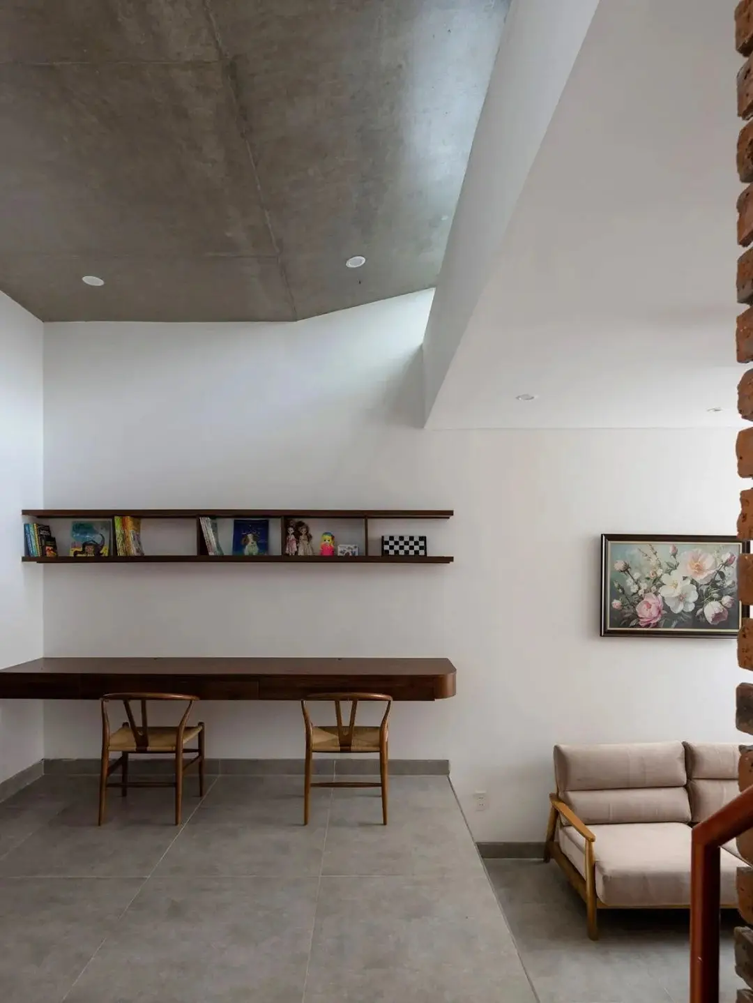 نمای خارجی مدرن خانه برنج قهوه‌ای با ترکیب آجرهای سفالی ترکوتا، بلوک‌های شیشه‌ای رنگی و فضای سبز که نشان‌دهنده معماری پایدار و نورپردازی طبیعی است.