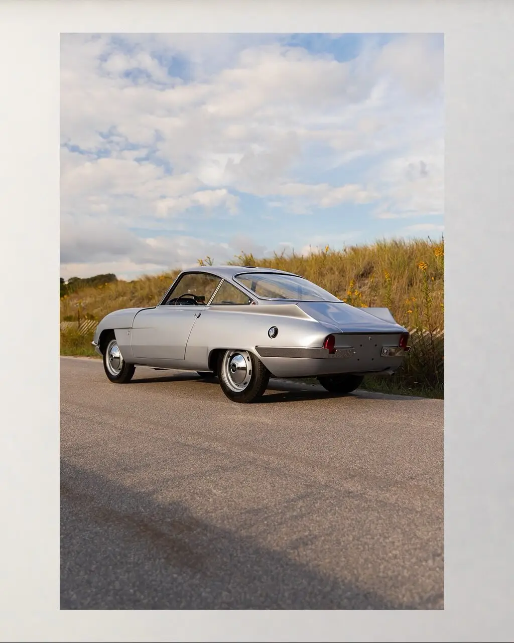 نمای نزدیک از طراحی آیرودینامیک و بدنه مجسمه‌گونه یک خودروی کلاسیک برتونه متعلق به اواخر دهه ۱۹۵۰ با باله‌های نمادین و خطوط تیز بدنه.