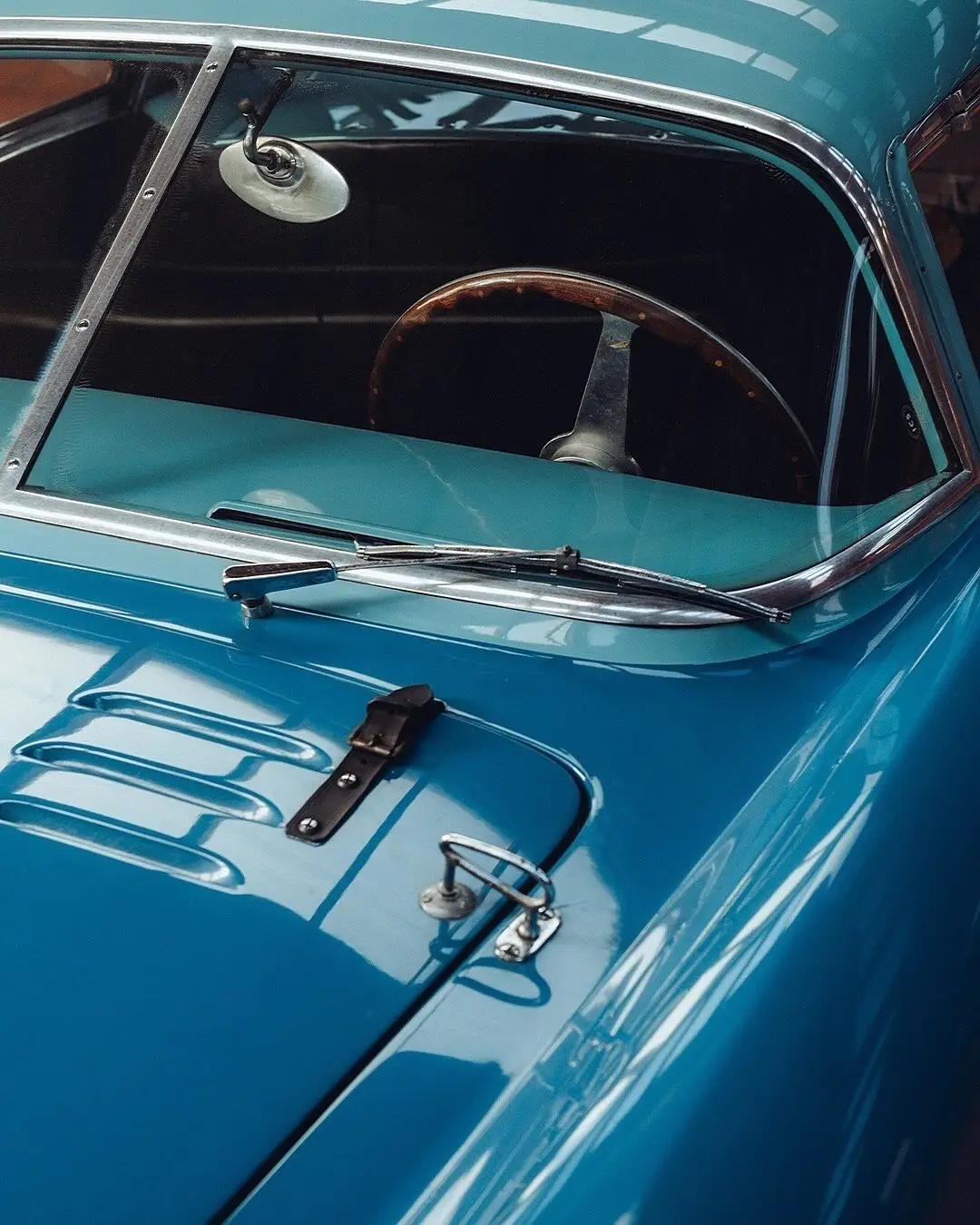 نمای جلویی و جانبی خودروی کلاسیک مازراتی A6GCS فارینا برلینتا به رنگ آبی متالیک با رینگ‌های پره‌ای در مقابل یک بنای سنتی اروپایی.