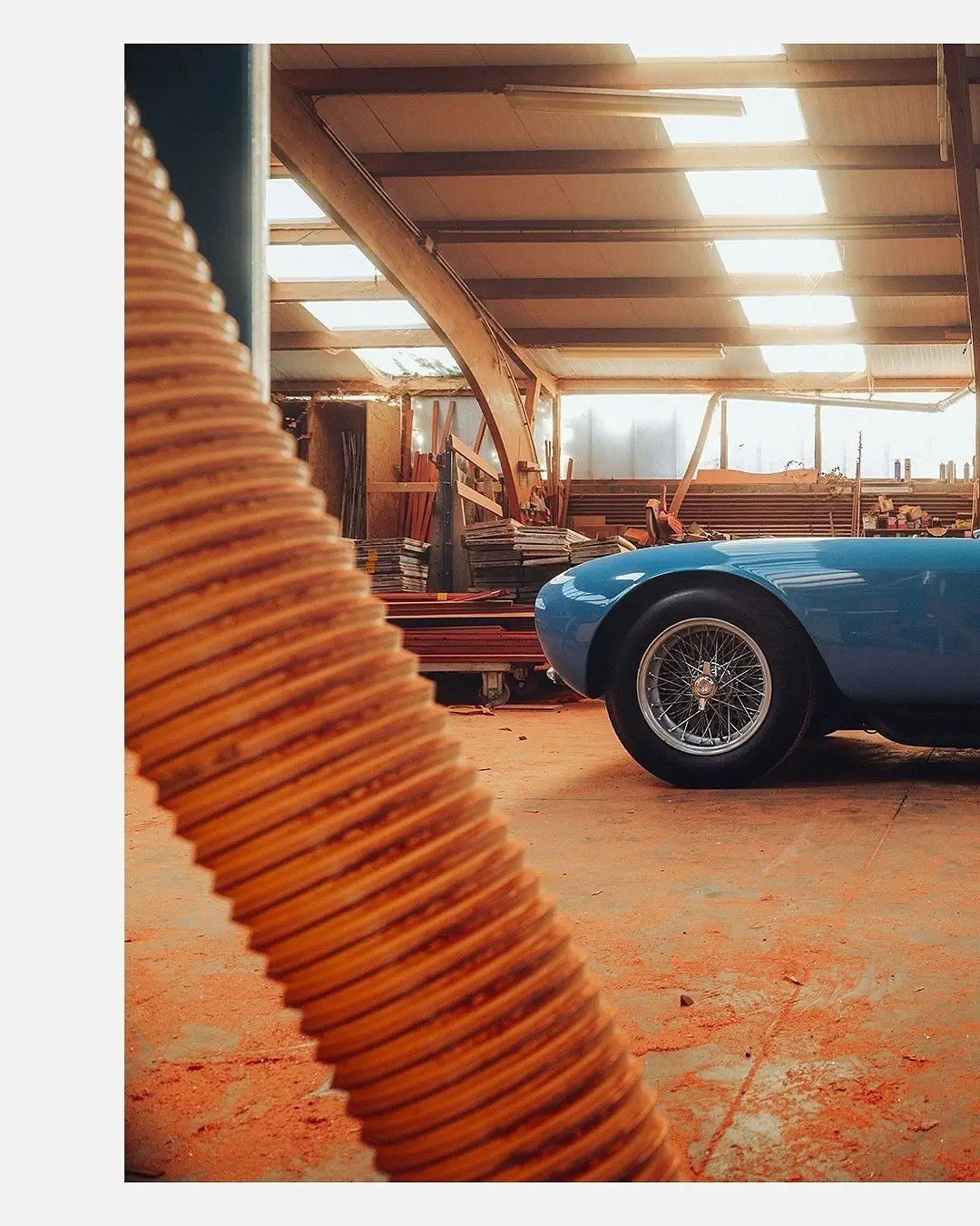 نمای جلویی و جانبی خودروی کلاسیک مازراتی A6GCS فارینا برلینتا به رنگ آبی متالیک با رینگ‌های پره‌ای در مقابل یک بنای سنتی اروپایی.