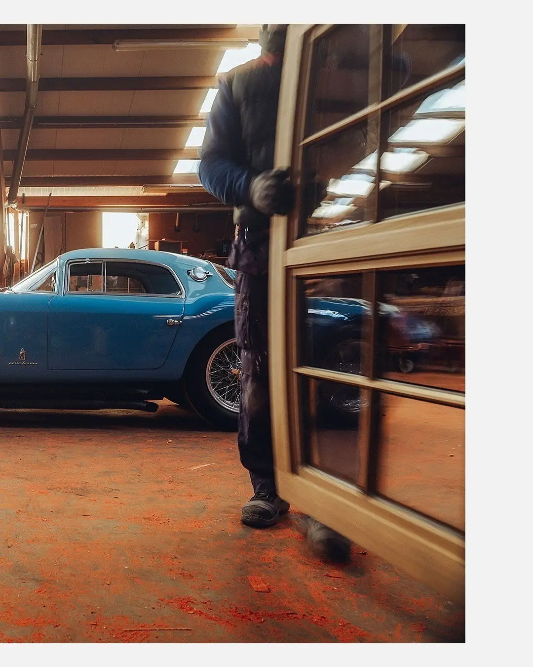 نمای جلویی و جانبی خودروی کلاسیک مازراتی A6GCS فارینا برلینتا به رنگ آبی متالیک با رینگ‌های پره‌ای در مقابل یک بنای سنتی اروپایی.