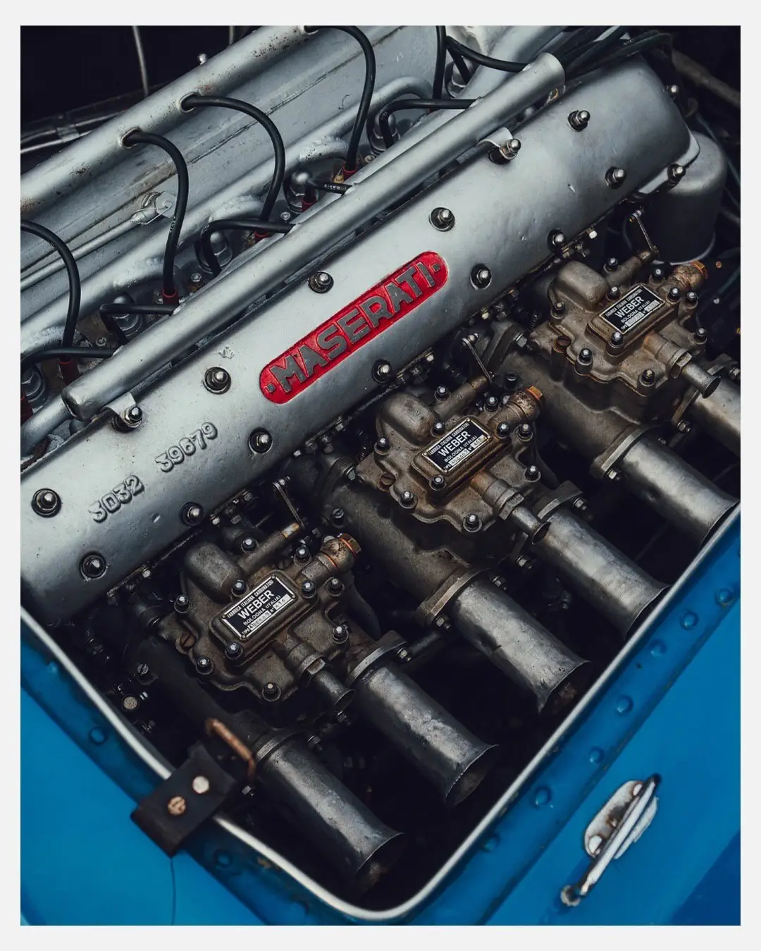 نمای جلویی و جانبی خودروی کلاسیک مازراتی A6GCS فارینا برلینتا به رنگ آبی متالیک با رینگ‌های پره‌ای در مقابل یک بنای سنتی اروپایی.