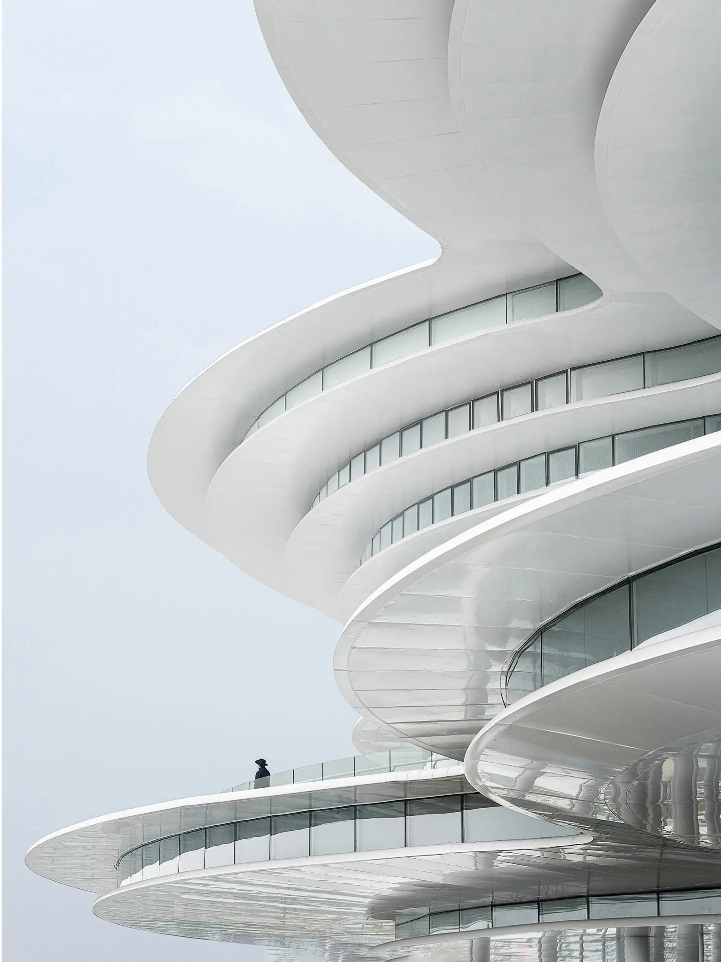 نمای ساختمان مدرن و معلق مرکز نمایشگاهی ابر فرودگاه چنگدو با طراحی سفید و کشیده بر فراز فضای سبز که نشان‌دهنده سبک معماری انتزاعی شرکت CSWADI است.