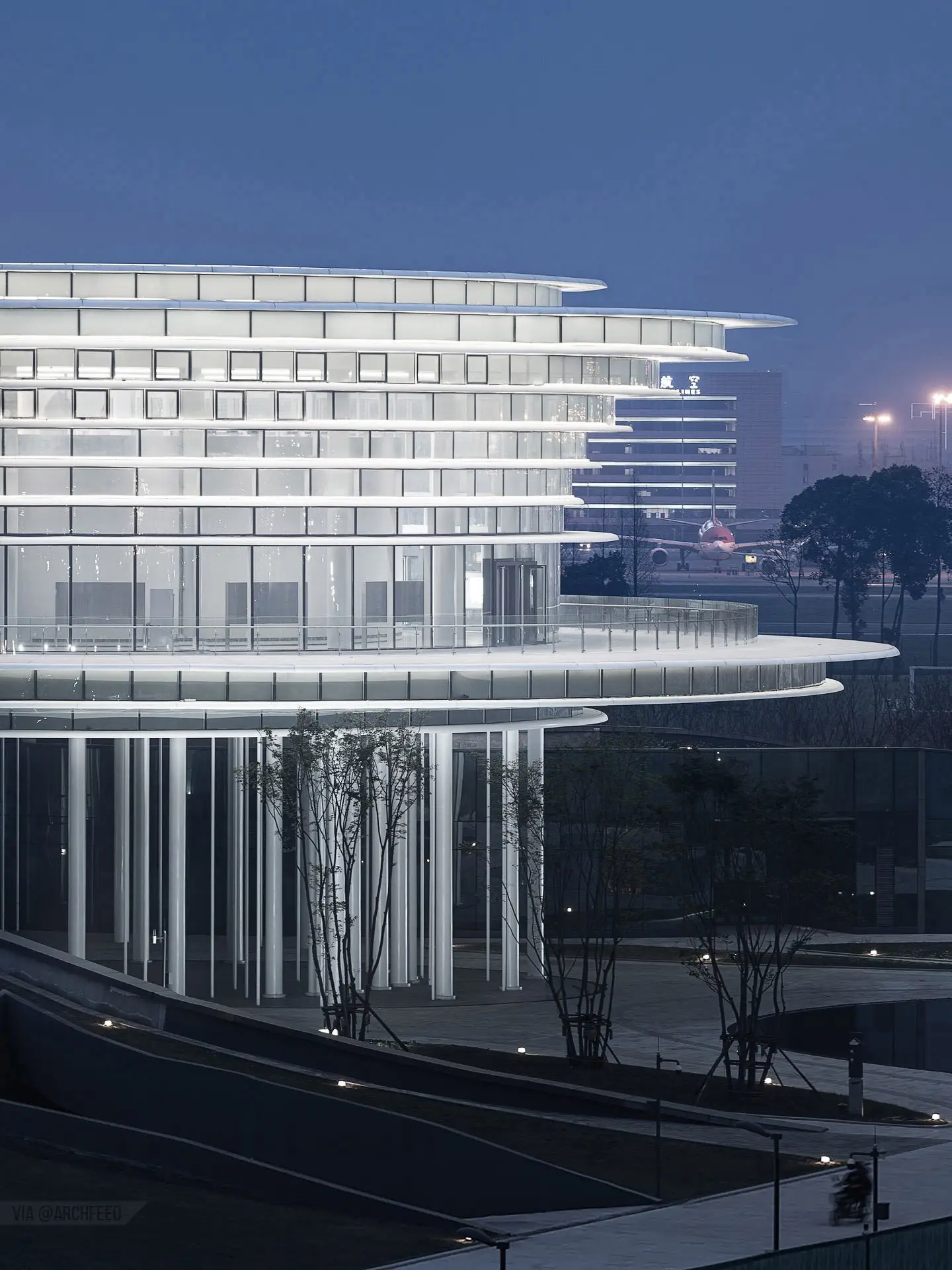 نمای ساختمان مدرن و معلق مرکز نمایشگاهی ابر فرودگاه چنگدو با طراحی سفید و کشیده بر فراز فضای سبز که نشان‌دهنده سبک معماری انتزاعی شرکت CSWADI است.