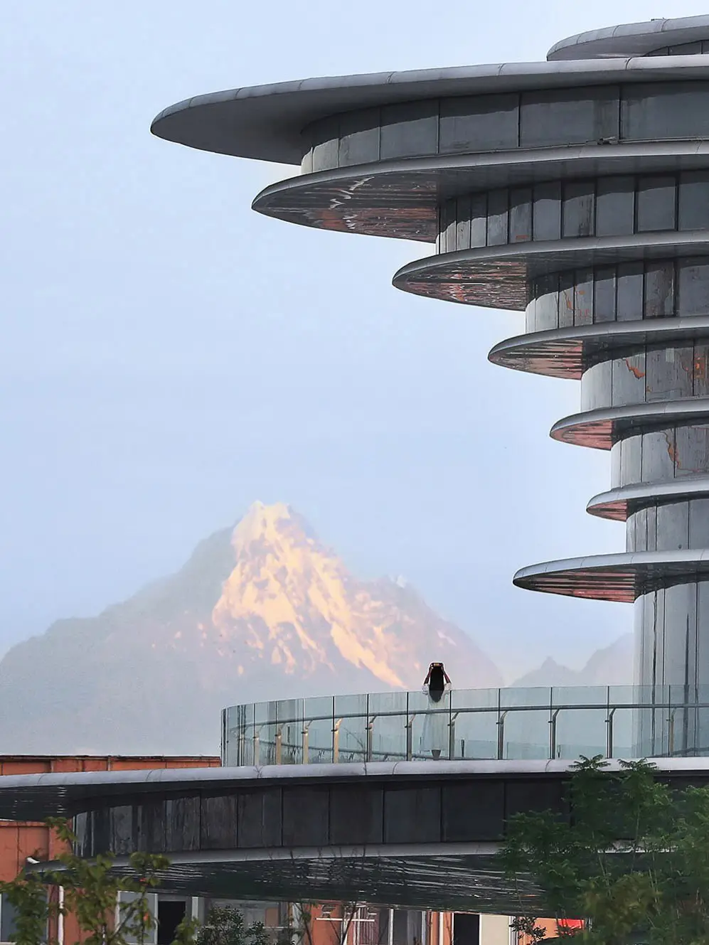 نمای ساختمان مدرن و معلق مرکز نمایشگاهی ابر فرودگاه چنگدو با طراحی سفید و کشیده بر فراز فضای سبز که نشان‌دهنده سبک معماری انتزاعی شرکت CSWADI است.