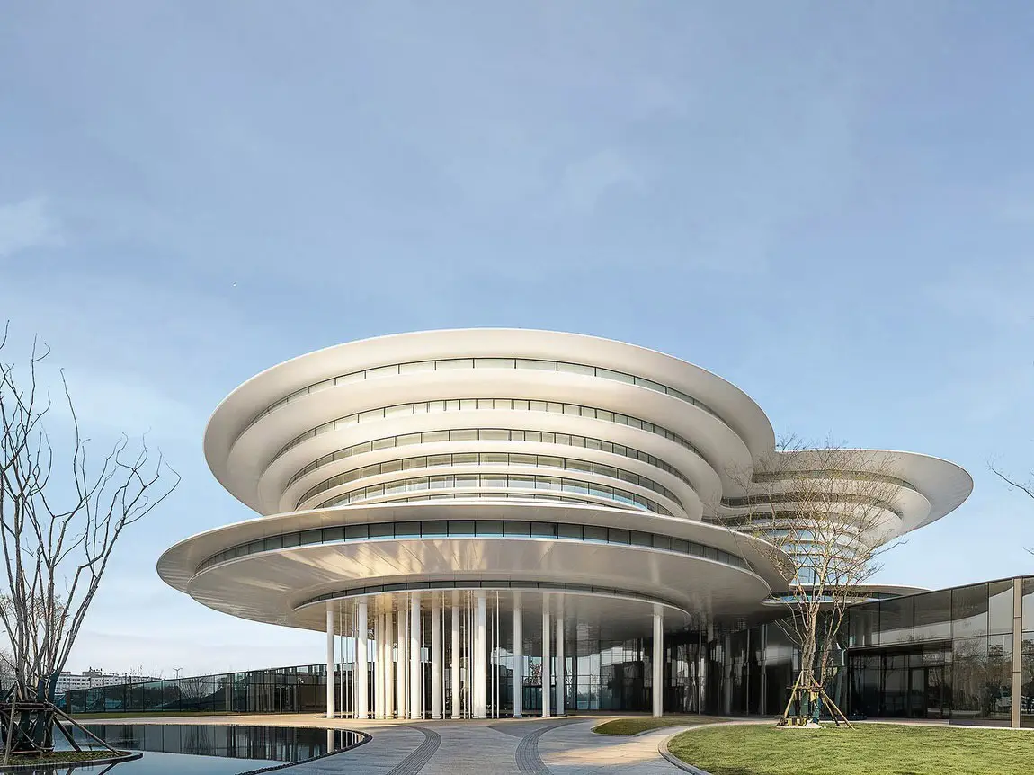 نمای ساختمان مدرن و معلق مرکز نمایشگاهی ابر فرودگاه چنگدو با طراحی سفید و کشیده بر فراز فضای سبز که نشان‌دهنده سبک معماری انتزاعی شرکت CSWADI است.