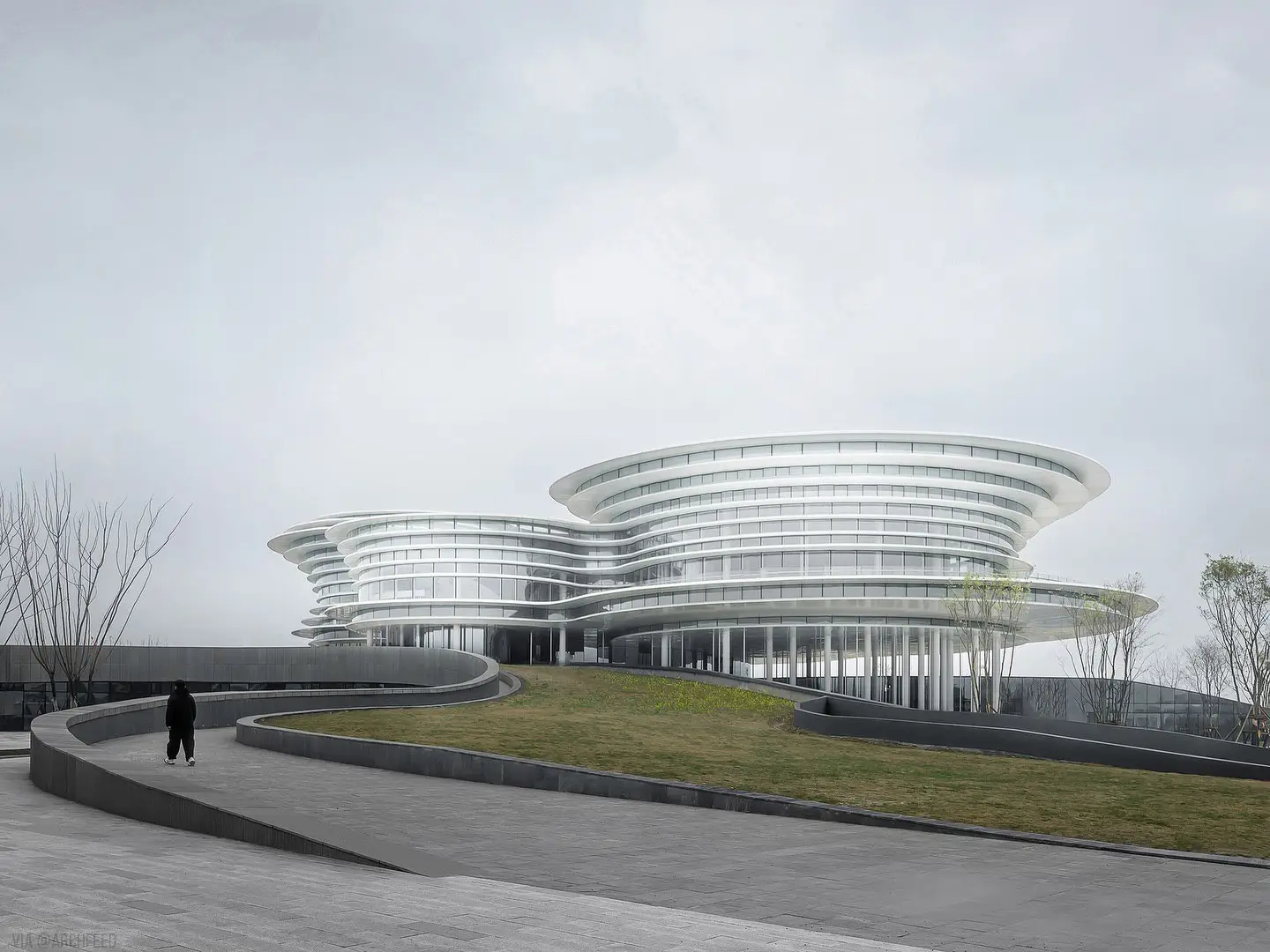 نمای ساختمان مدرن و معلق مرکز نمایشگاهی ابر فرودگاه چنگدو با طراحی سفید و کشیده بر فراز فضای سبز که نشان‌دهنده سبک معماری انتزاعی شرکت CSWADI است.