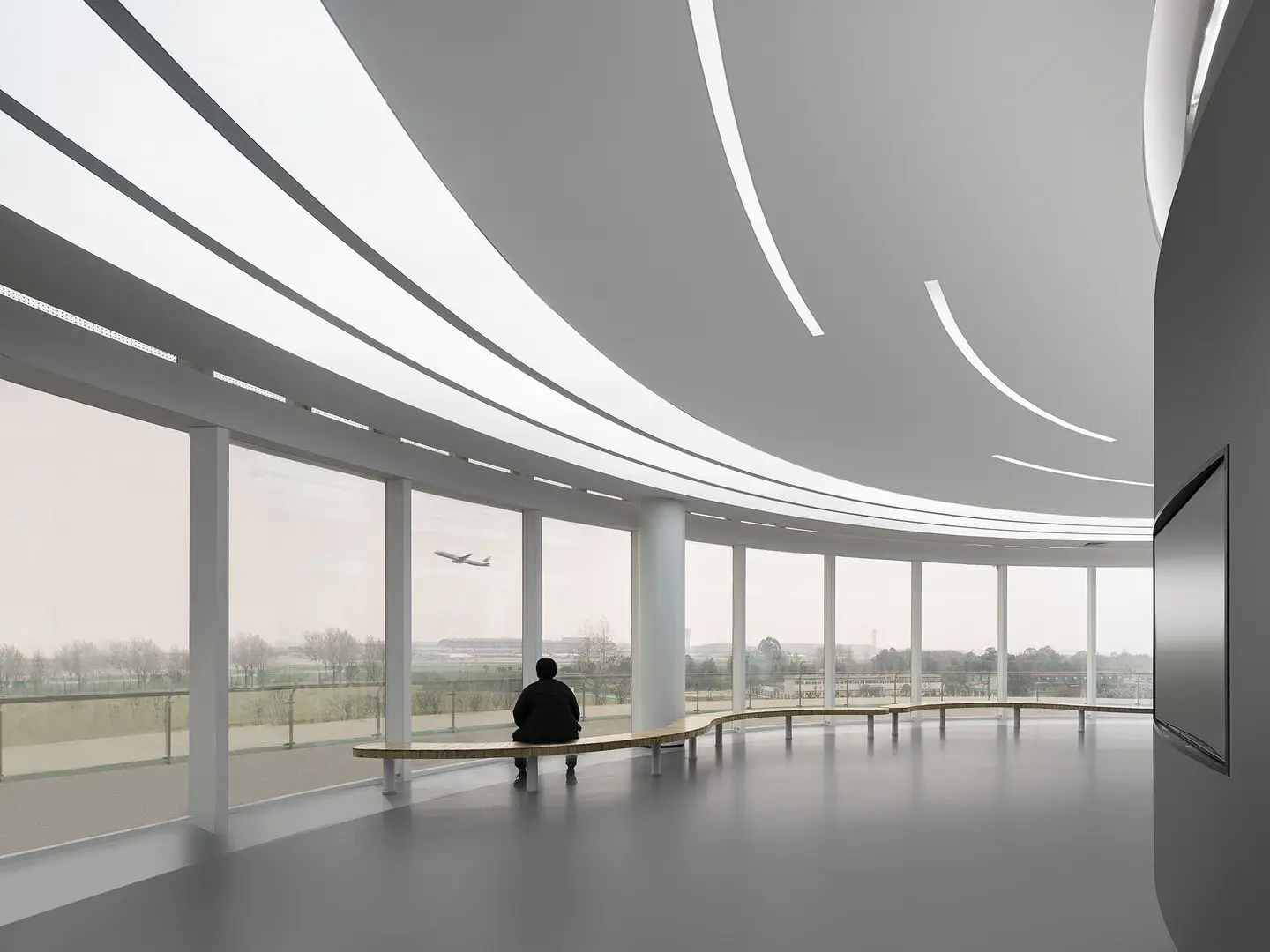 نمای ساختمان مدرن و معلق مرکز نمایشگاهی ابر فرودگاه چنگدو با طراحی سفید و کشیده بر فراز فضای سبز که نشان‌دهنده سبک معماری انتزاعی شرکت CSWADI است.