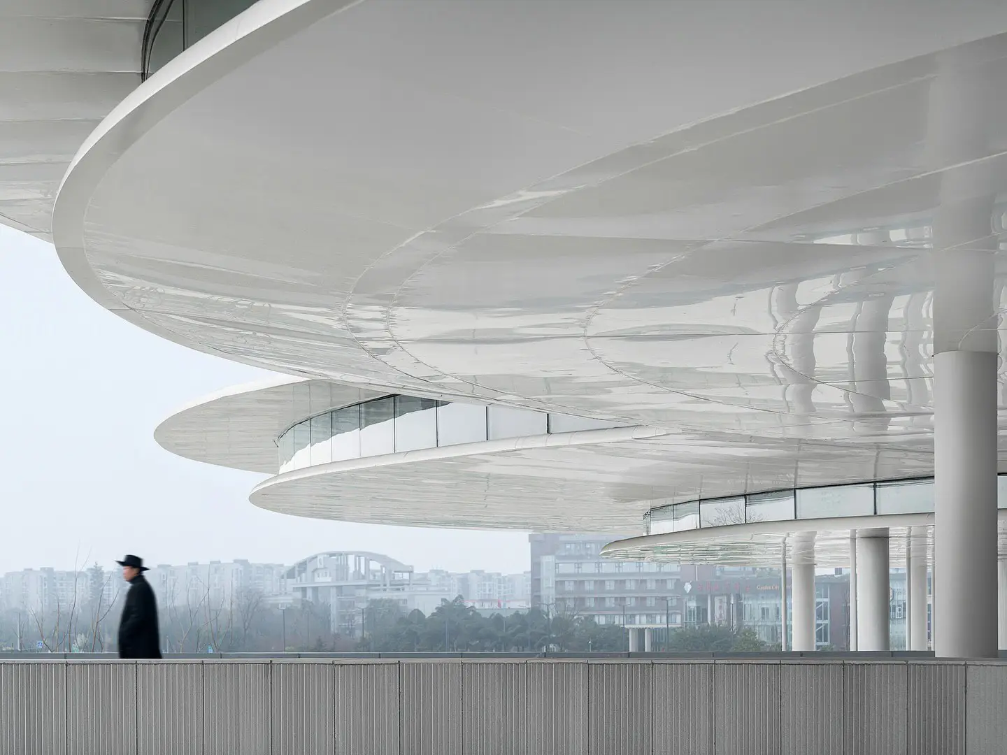نمای ساختمان مدرن و معلق مرکز نمایشگاهی ابر فرودگاه چنگدو با طراحی سفید و کشیده بر فراز فضای سبز که نشان‌دهنده سبک معماری انتزاعی شرکت CSWADI است.