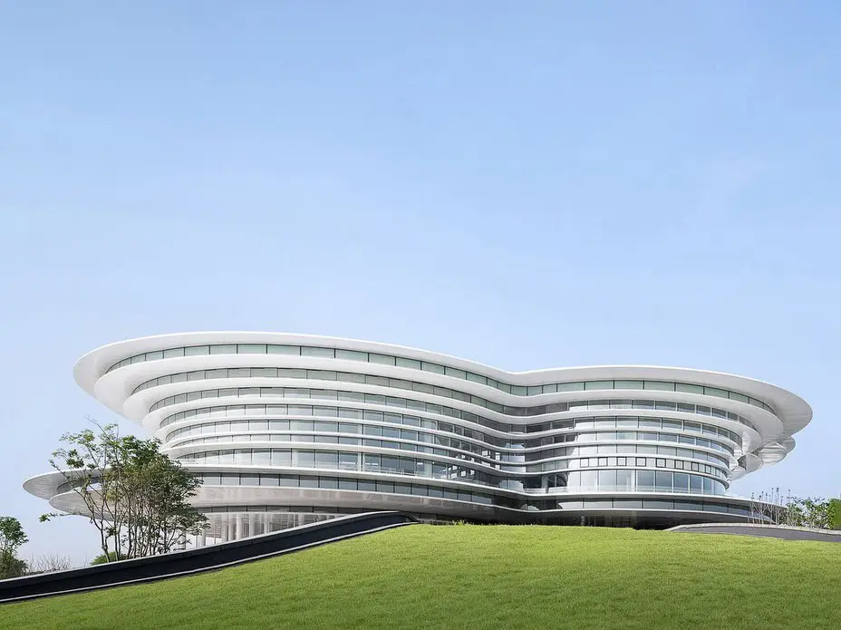 نمای ساختمان مدرن و معلق مرکز نمایشگاهی ابر فرودگاه چنگدو با طراحی سفید و کشیده بر فراز فضای سبز که نشان‌دهنده سبک معماری انتزاعی شرکت CSWADI است.