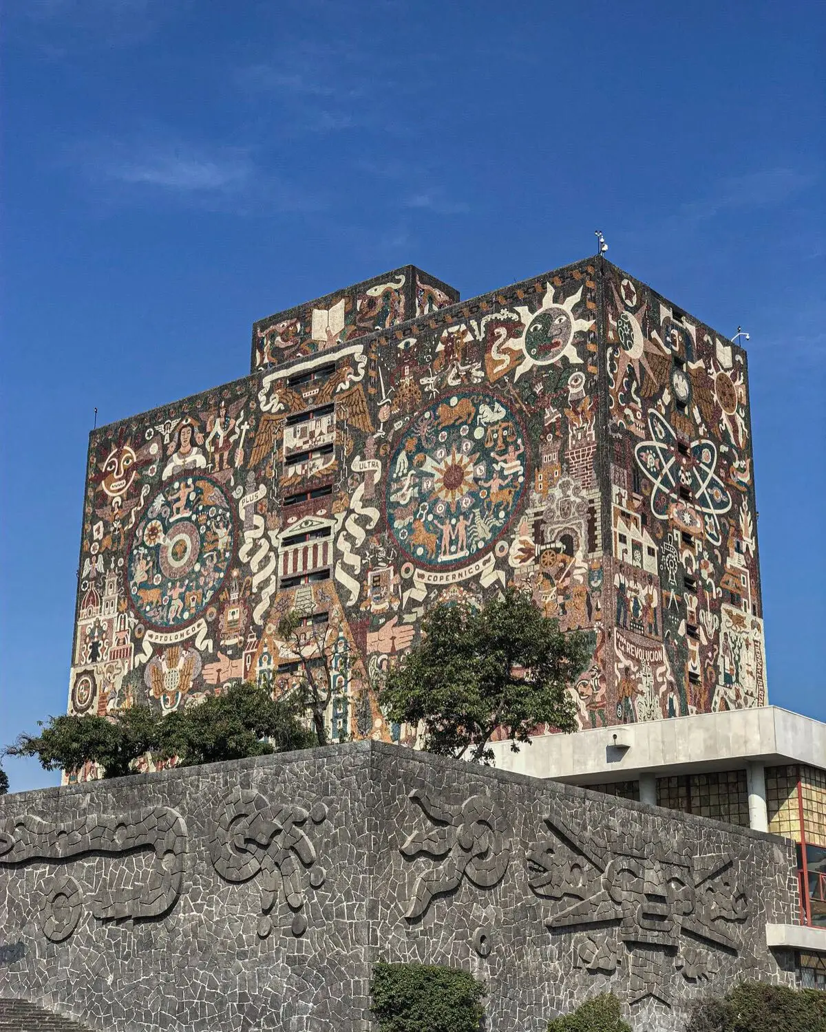 نمای ساختمان‌های بتنی به سبک بروتالیسم در مکزیک با هندسه صلب و سایه‌های عمیق که نشان‌دهنده ترکیب معماری مدرن و سنتی است.